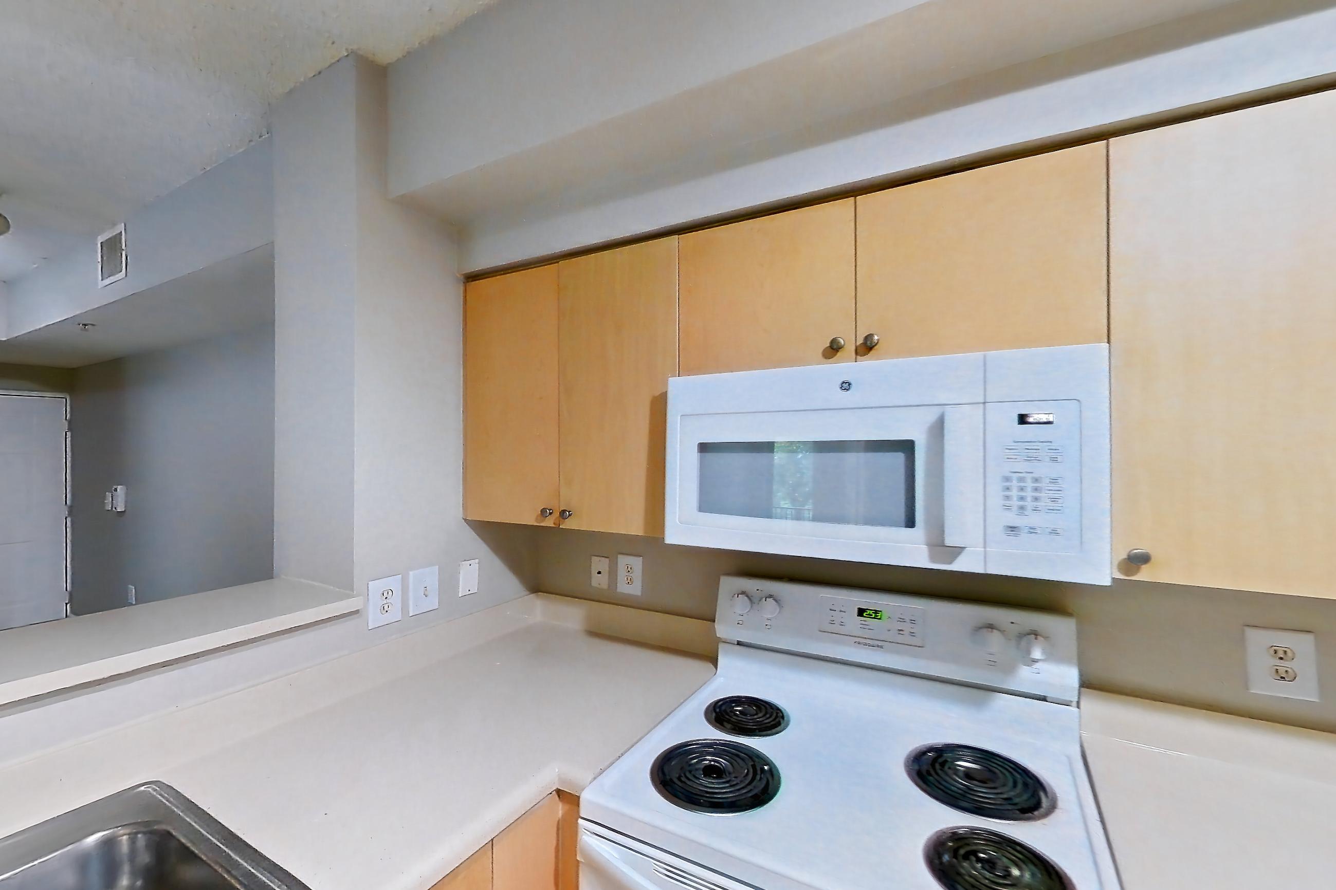 Kitchen with dishwasher, electric range, light countertops, light tile flooring, microwave, oven/range, refrigerator, and white appliances, Apartment 12-207 at Miramar Lakes