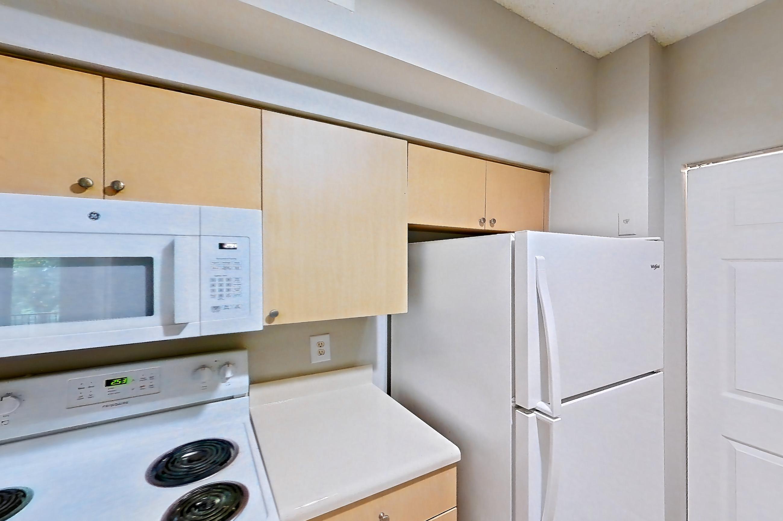 Kitchen with dishwasher, electric range, light countertops, light tile flooring, microwave, oven/range, refrigerator, and white appliances, Apartment 12-207 at Miramar Lakes