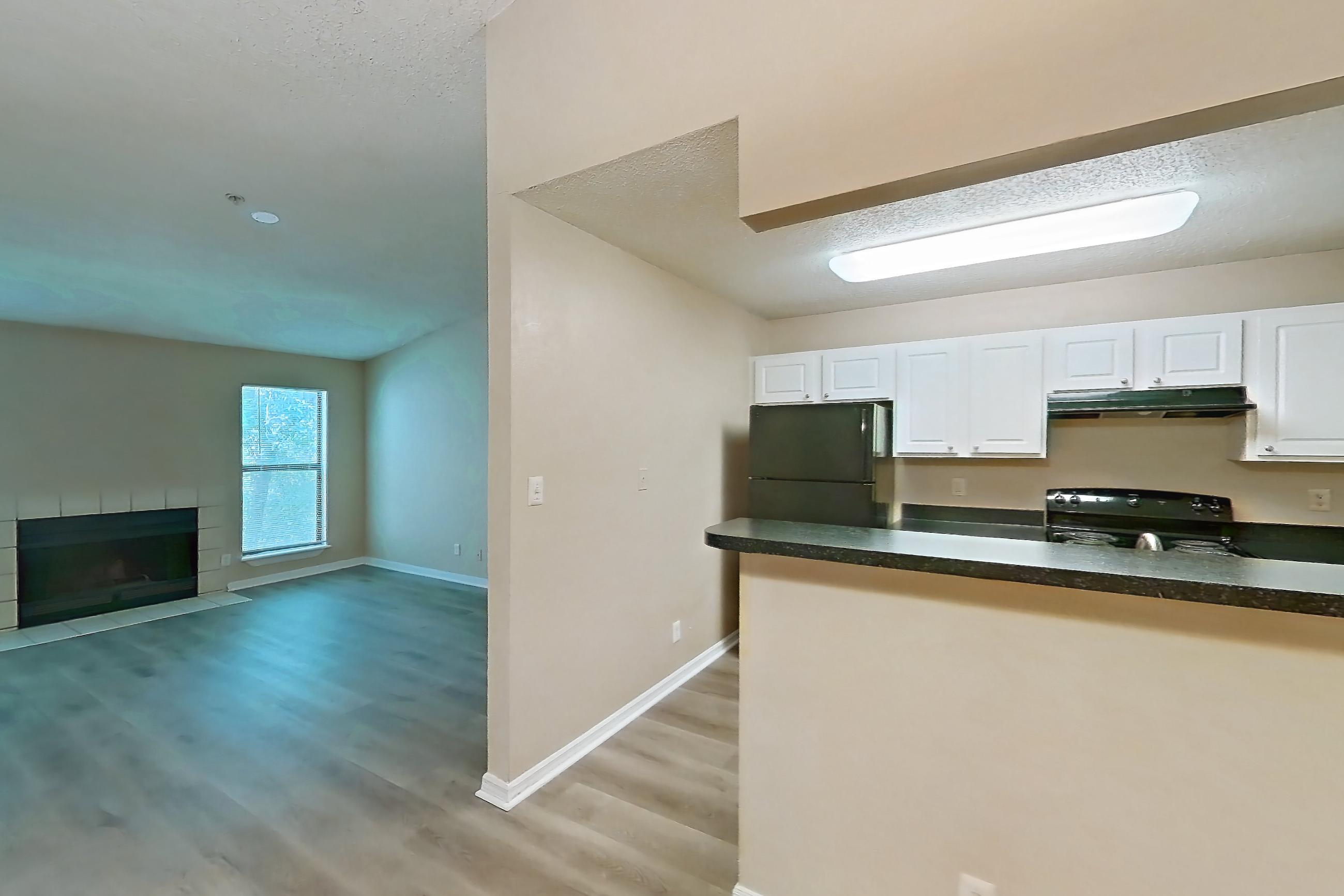 Dining room with black appliances, dark countertops, electric range, fireplace, light countertops, light wood-finish flooring, oven/range, range hood, and tile fireplace, Apartment 0222 at The Dawson
