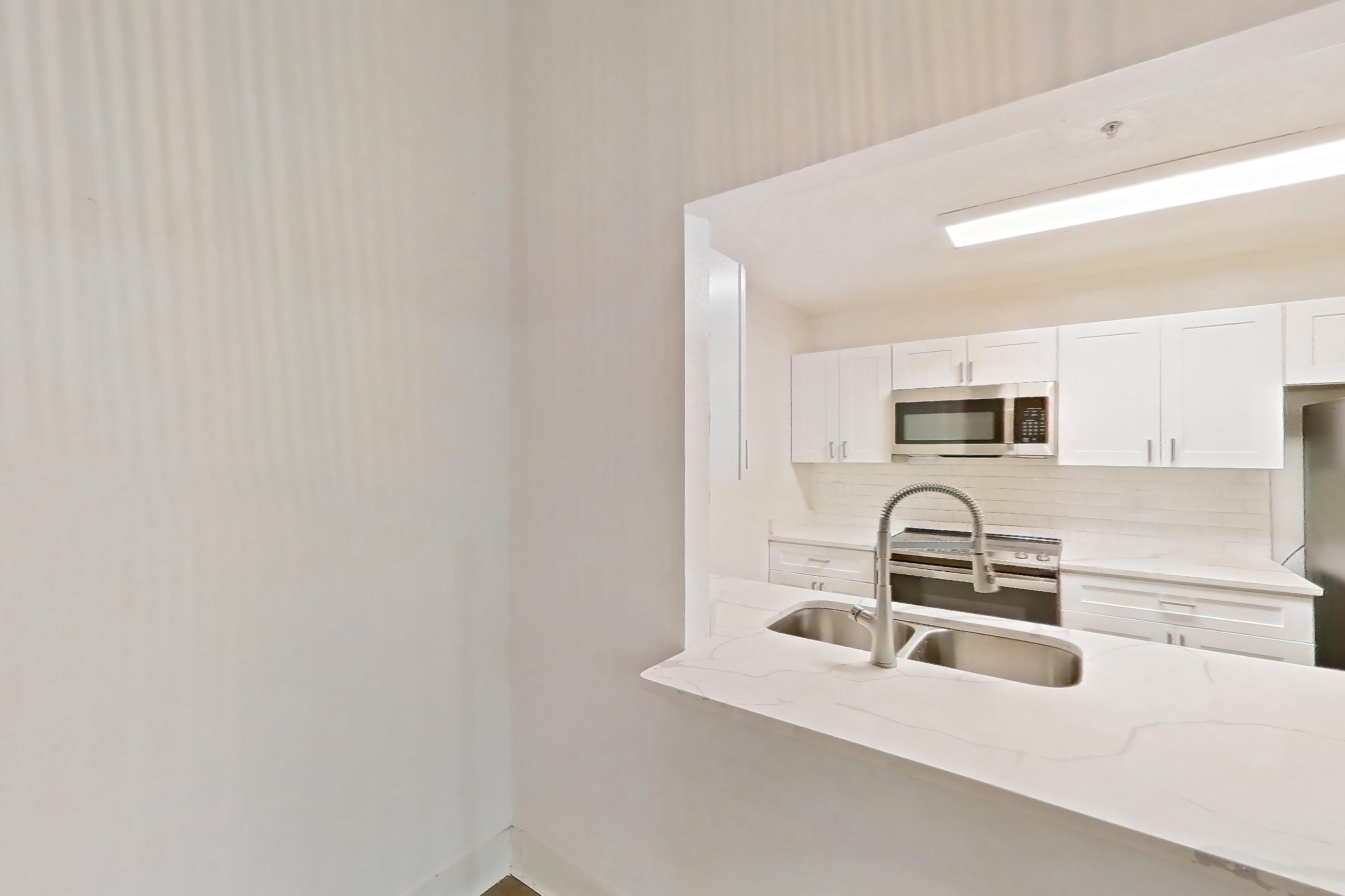 Dining room with light countertops, light stone countertops, light wood-finish flooring, microwave, refrigerator, and stainless steel appliances, Apartment 0211 at The Dawson