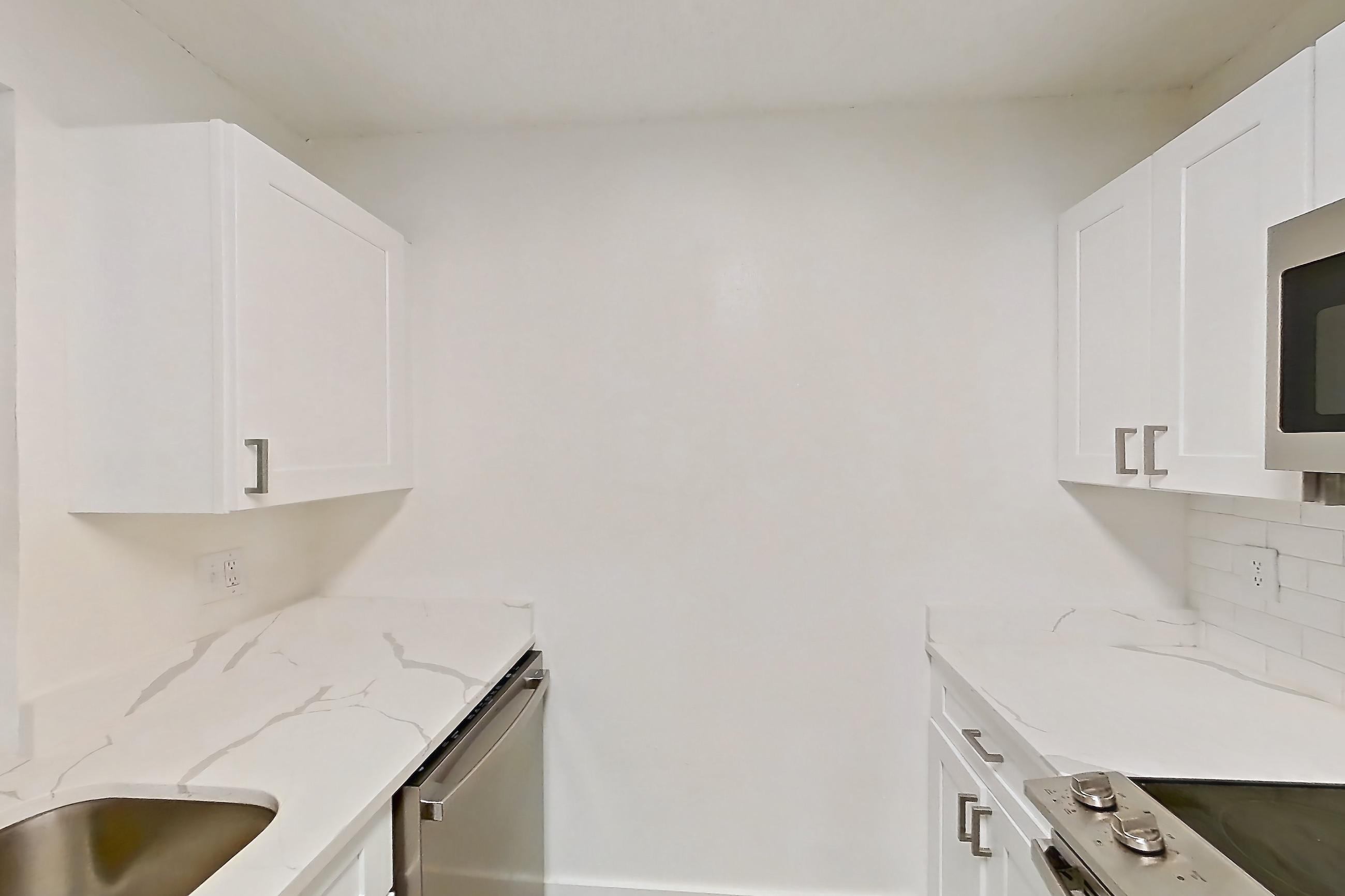 Kitchen with dishwasher, electric range, light countertops, light stone countertops, light wood-finish flooring, microwave, oven/range, and stainless steel appliances, Apartment 0211 at The Dawson