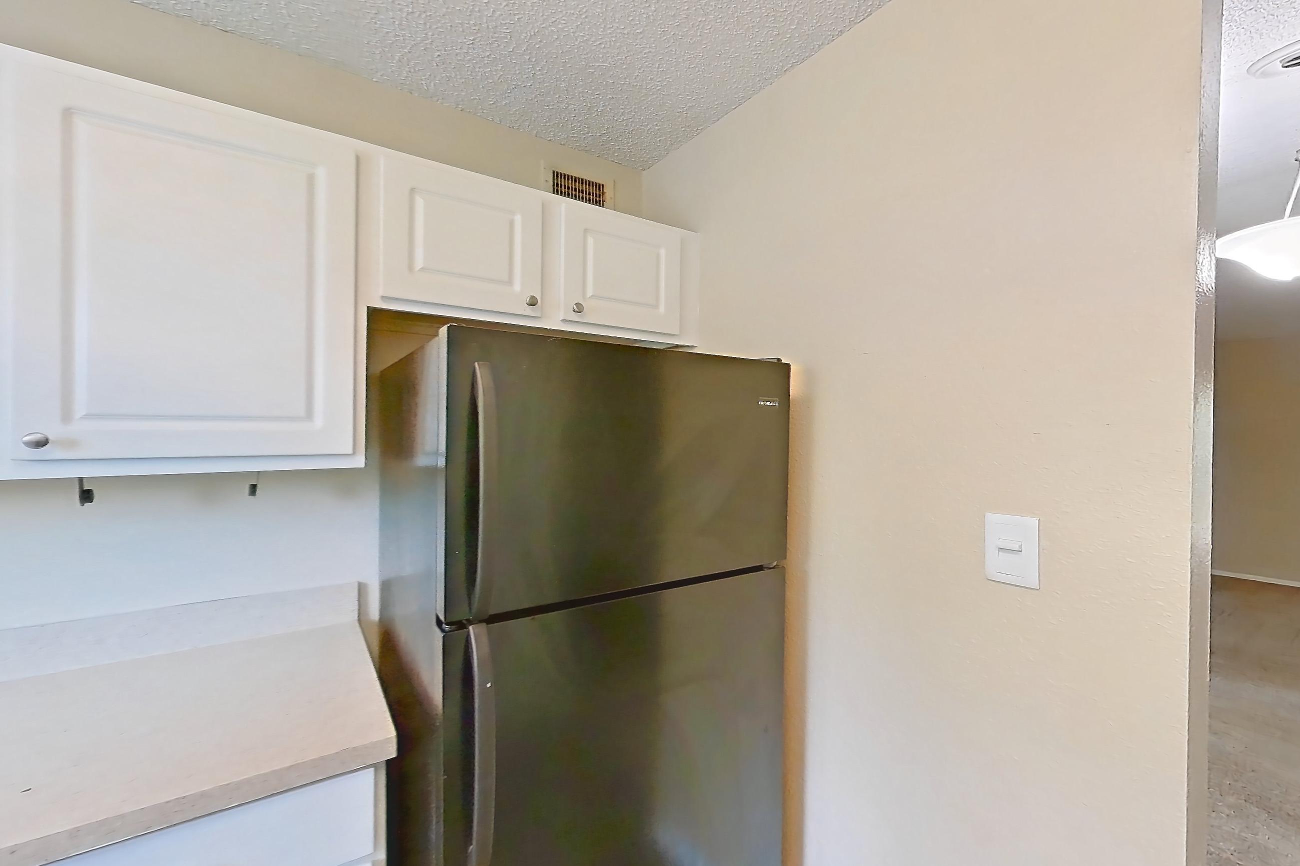 Kitchen with black appliances, dark wood-finish flooring, dishwasher, electric range, light countertops, oven/range, range hood, and refrigerator, Apartment 0707 at The Dawson