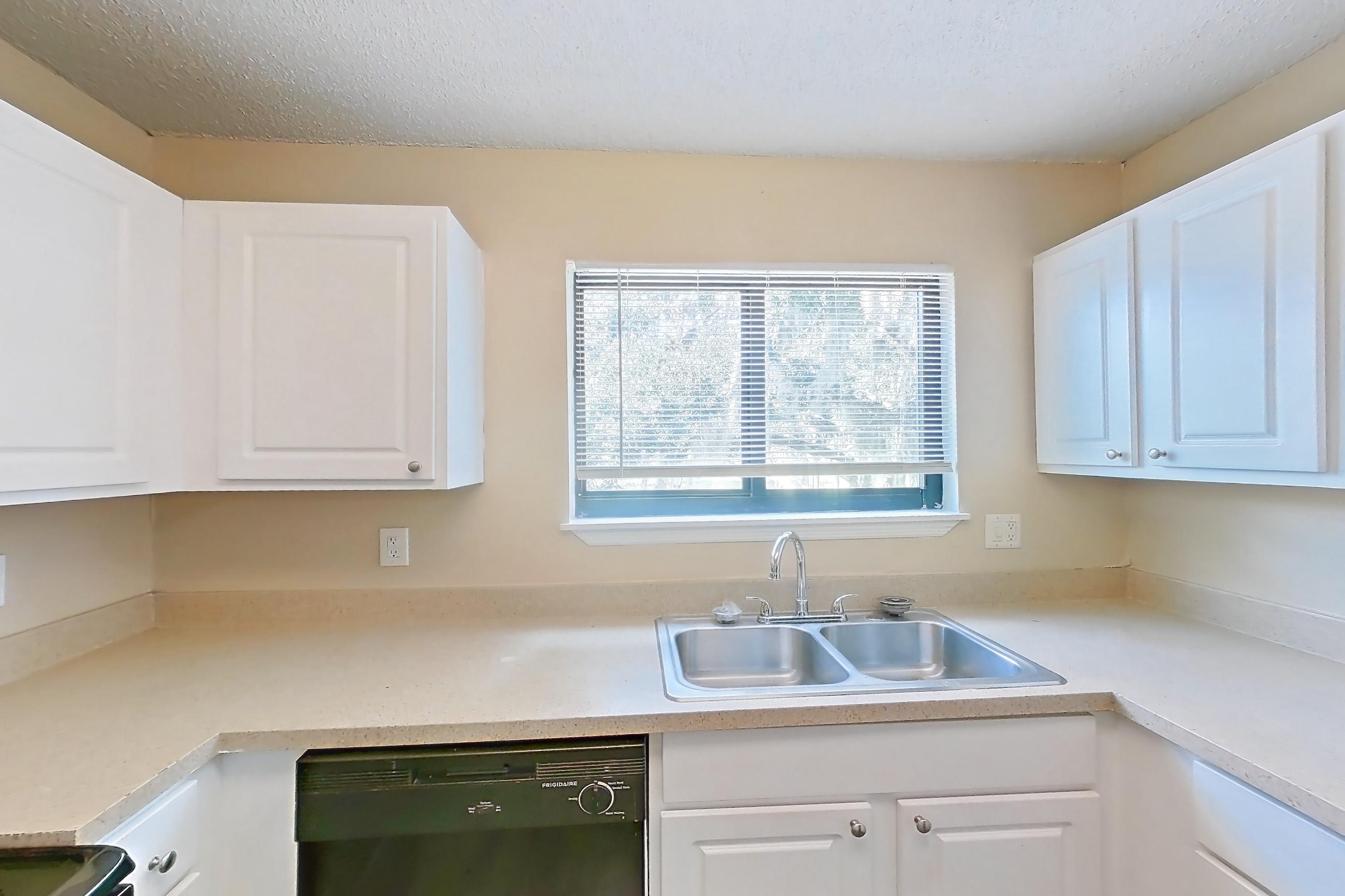 Kitchen with black appliances, dark wood-finish flooring, dishwasher, electric range, light countertops, oven/range, range hood, and refrigerator, Apartment 0707 at The Dawson