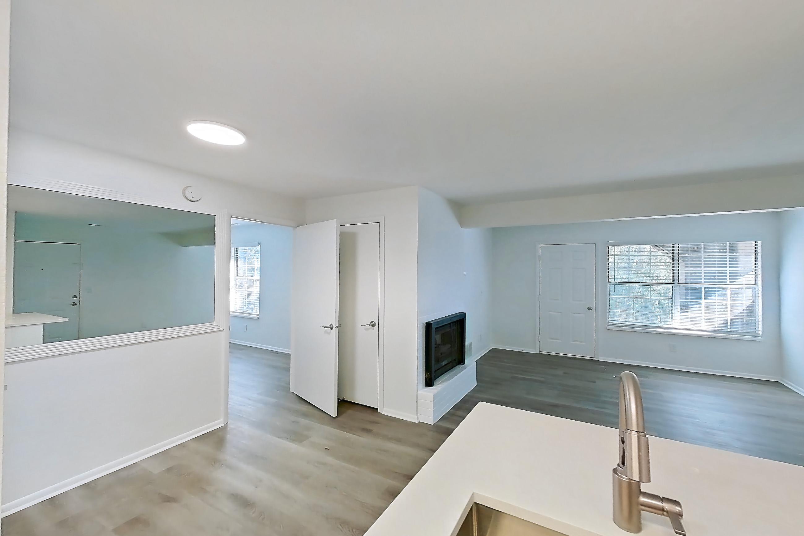 Kitchen with dishwasher, electric range, fireplace, light countertops, light wood-finish flooring, oven/range, and stainless steel appliances, Apartment 16L at Stillwater