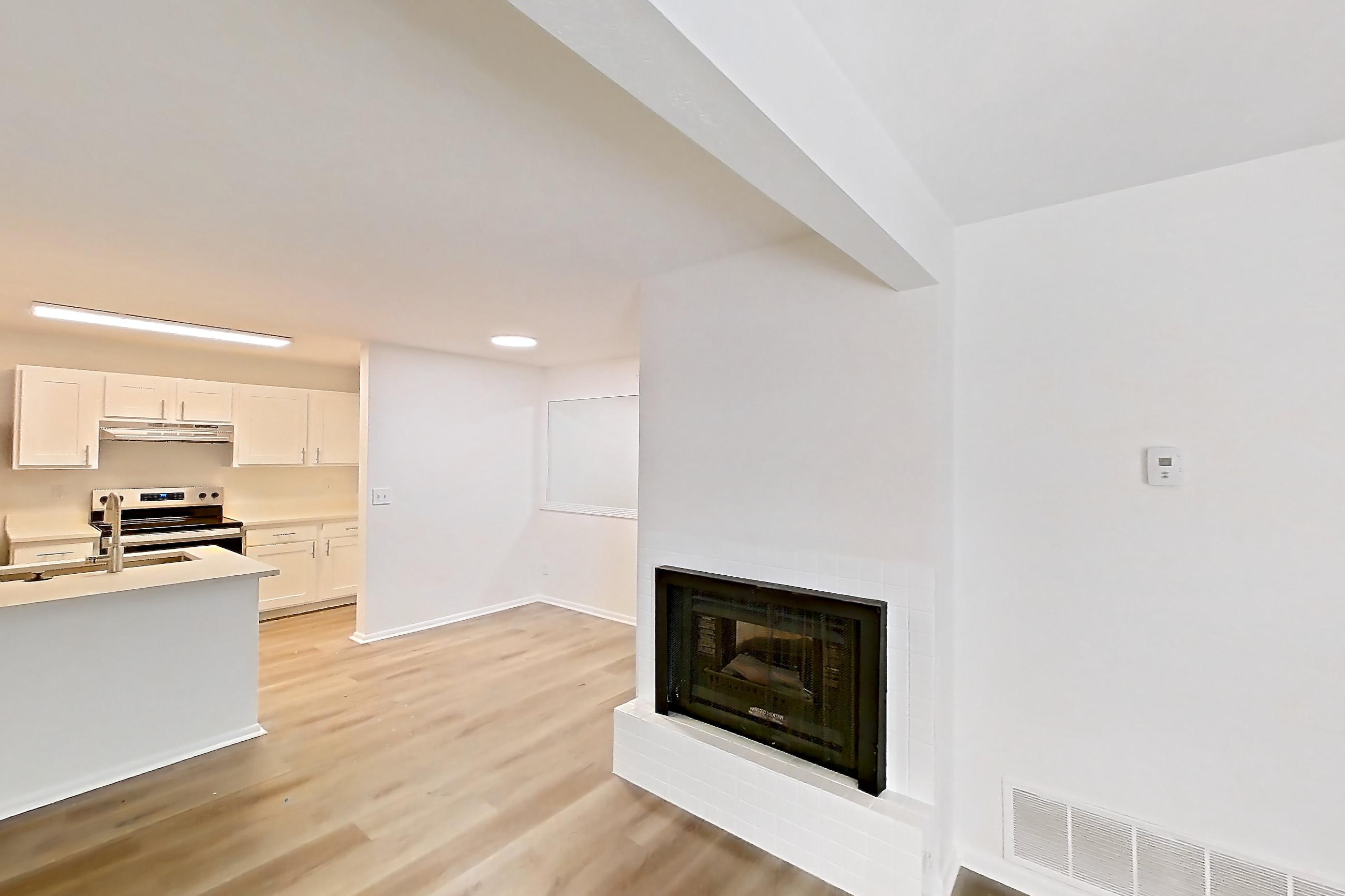Living room with dark wood-finish flooring, electric range, fireplace, light wood-finish flooring, oven/range, and stainless steel appliances, Apartment 16L at Stillwater