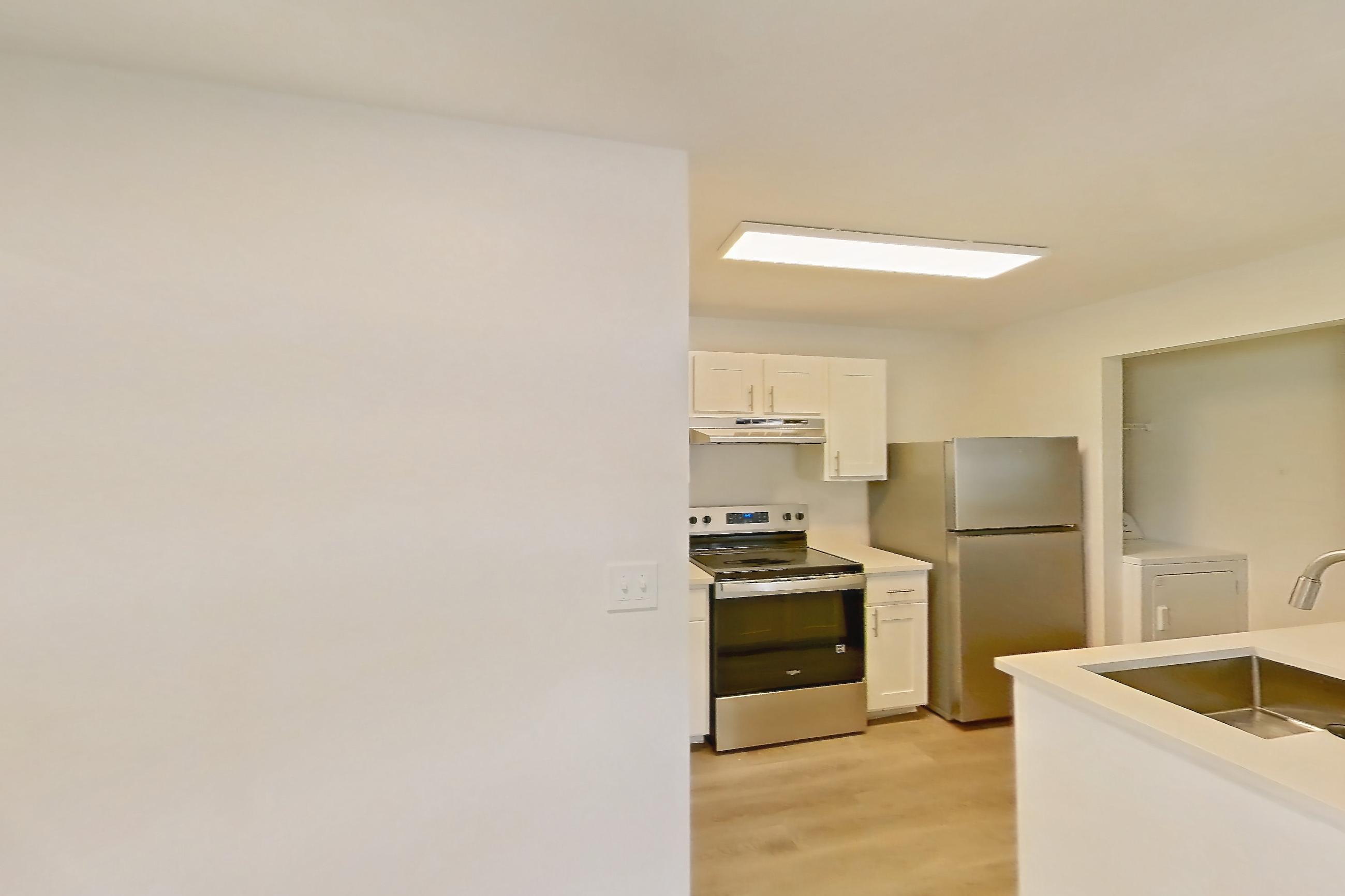 Dining room with electric range, in-unit laundry, light countertops, light wood-finish flooring, oven/range, refrigerator, and stainless steel appliances, Apartment 18K at Stillwater