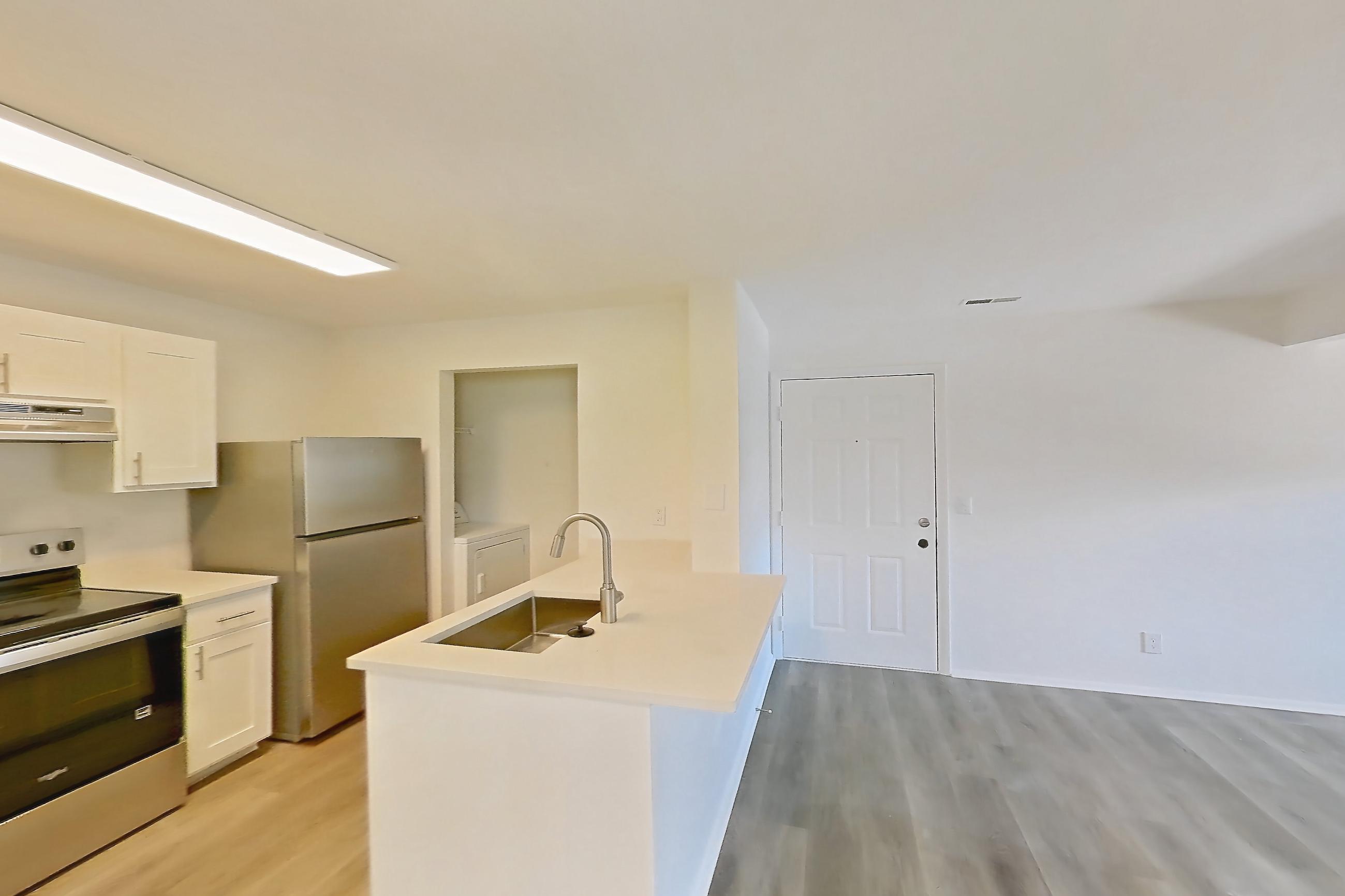 Dining room with electric range, in-unit laundry, light countertops, light wood-finish flooring, oven/range, refrigerator, and stainless steel appliances, Apartment 18K at Stillwater