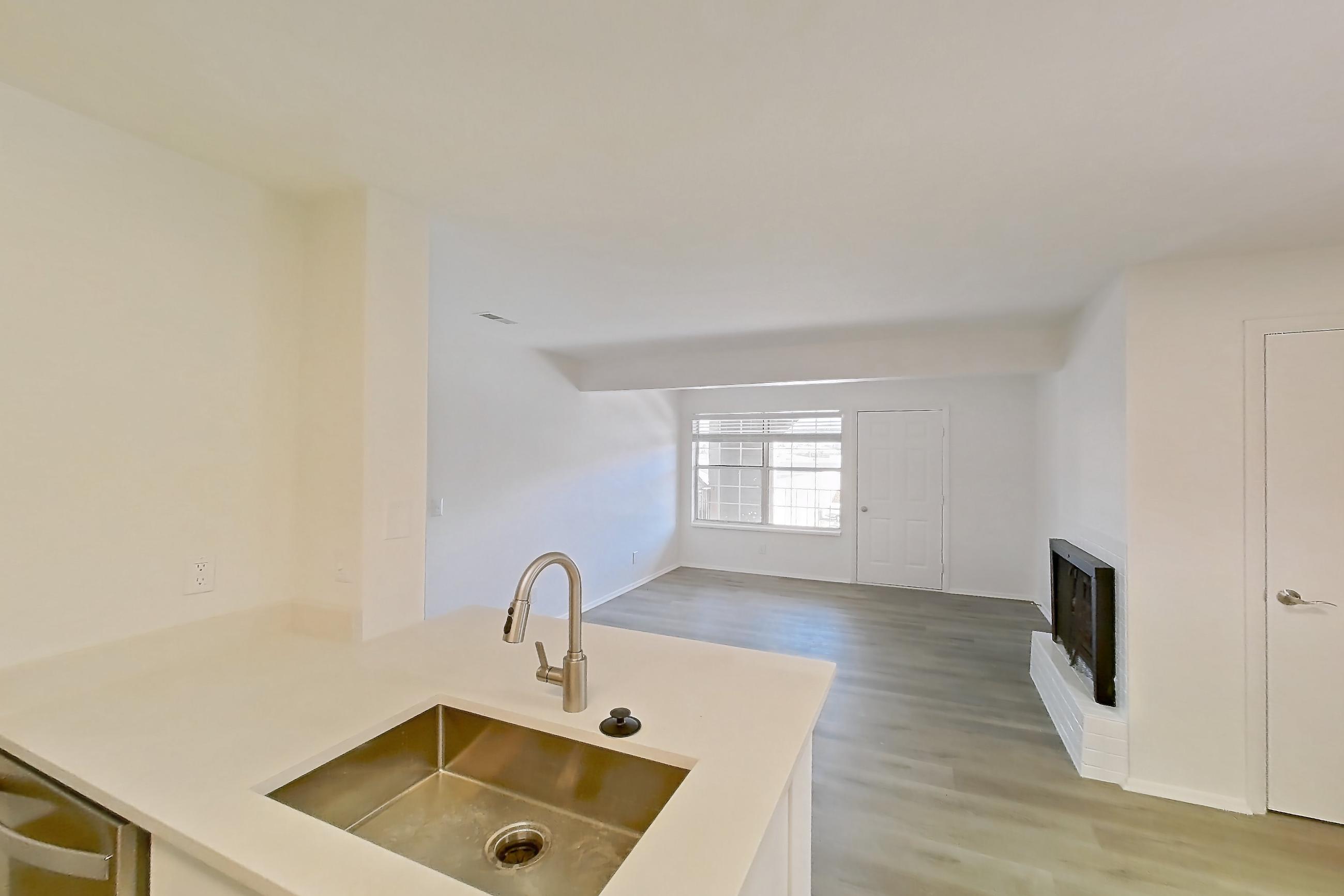 Kitchen with electric range, fireplace, light countertops, light wood-finish flooring, oven/range, refrigerator, and stainless steel appliances, Apartment 18K at Stillwater