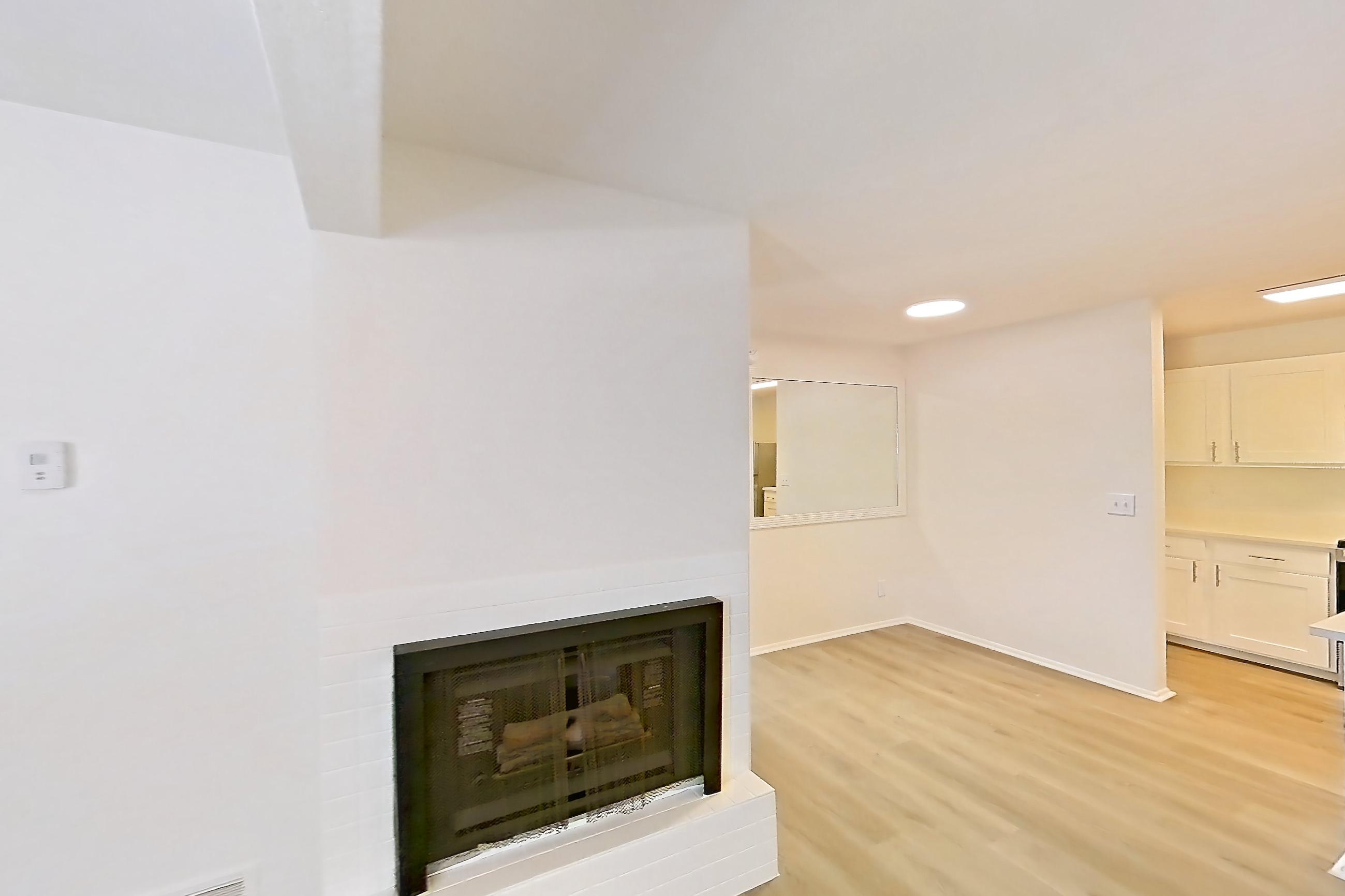 Living room with brick fireplace, fireplace, and light wood-finish flooring, Apartment 18K at Stillwater