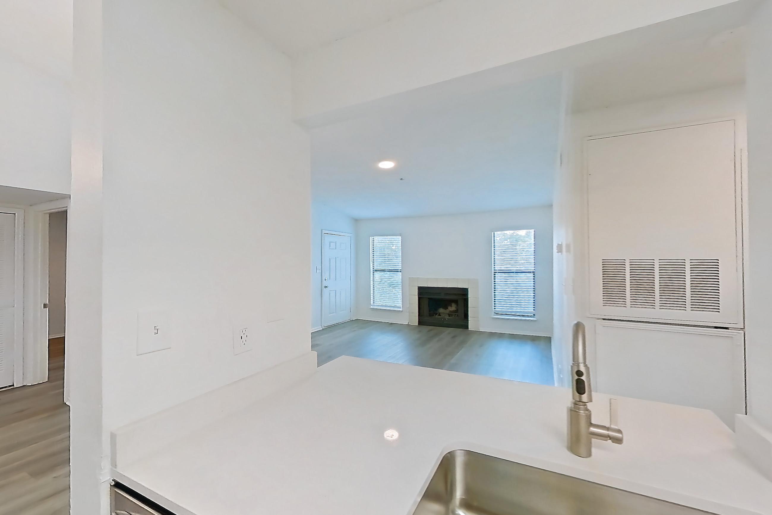Kitchen with electric range, fireplace, light countertops, light stone countertops, light wood-finish flooring, microwave, oven/range, refrigerator, stainless steel appliances, and tile fireplace, Apartment 1211 at The Dawson