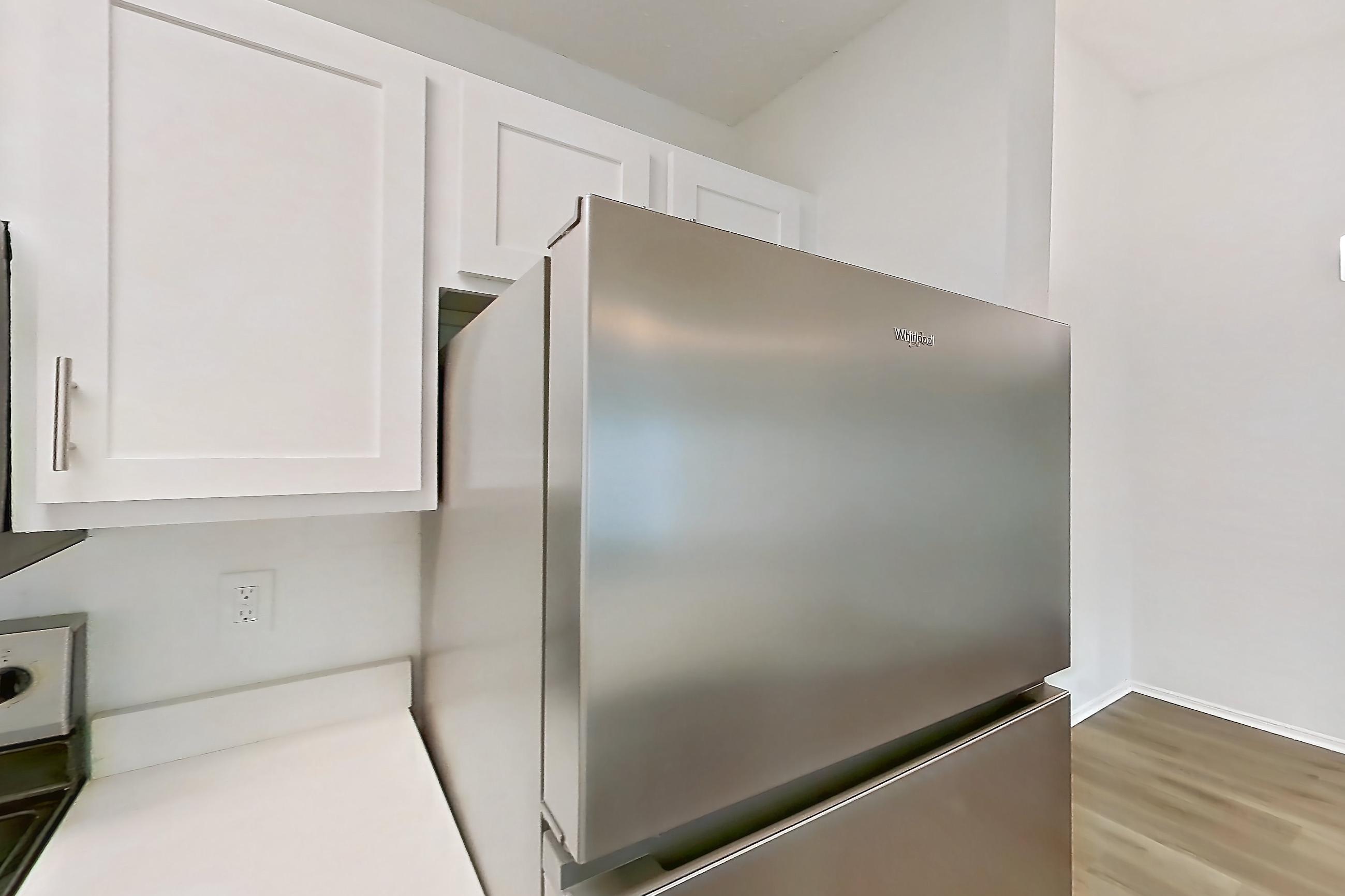 Kitchen with electric range, fireplace, light countertops, light stone countertops, light wood-finish flooring, microwave, oven/range, refrigerator, stainless steel appliances, and tile fireplace, Apartment 1211 at The Dawson