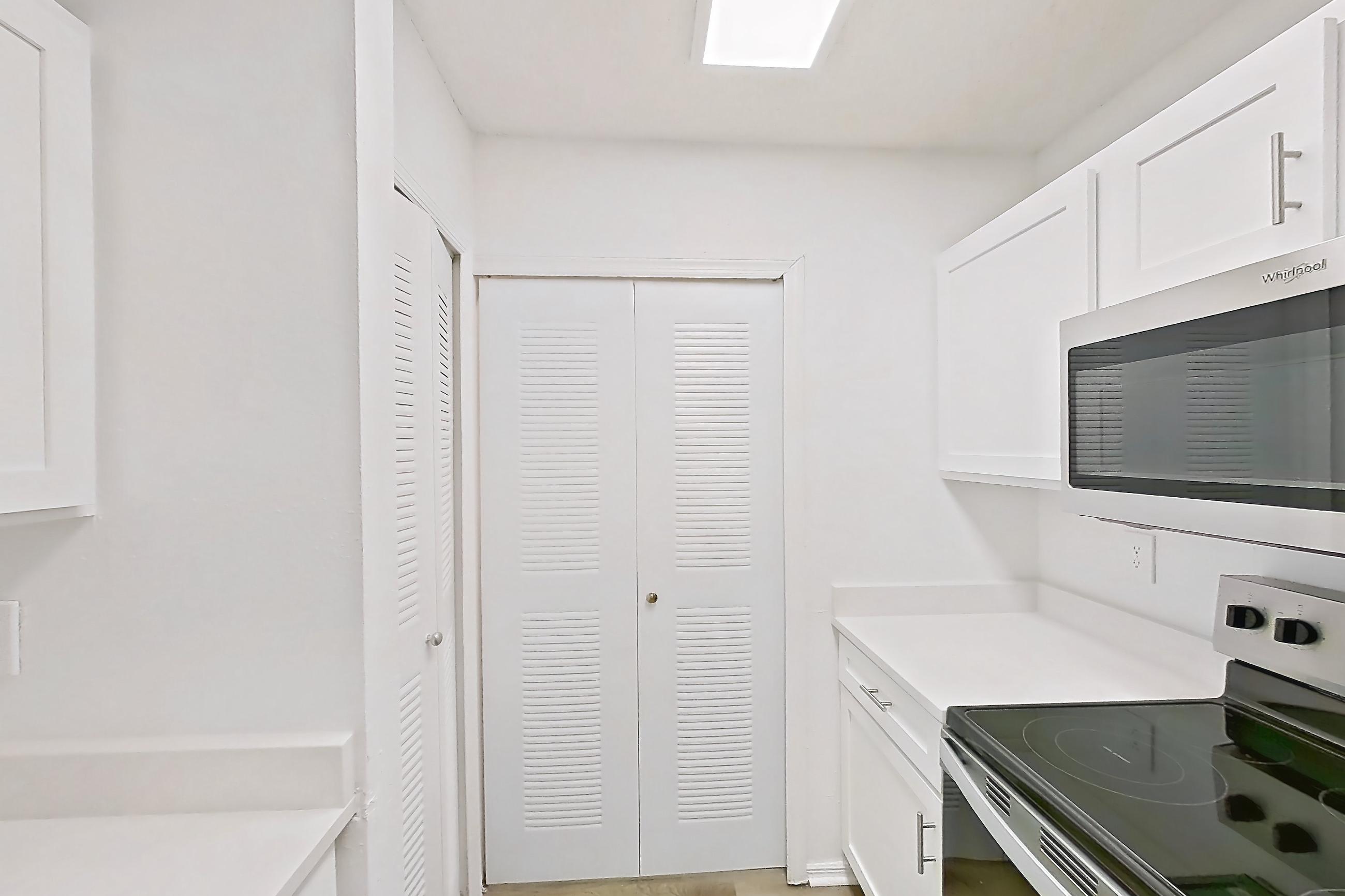 Kitchen with electric range, fireplace, light countertops, light stone countertops, light wood-finish flooring, microwave, oven/range, refrigerator, stainless steel appliances, and tile fireplace, Apartment 1211 at The Dawson
