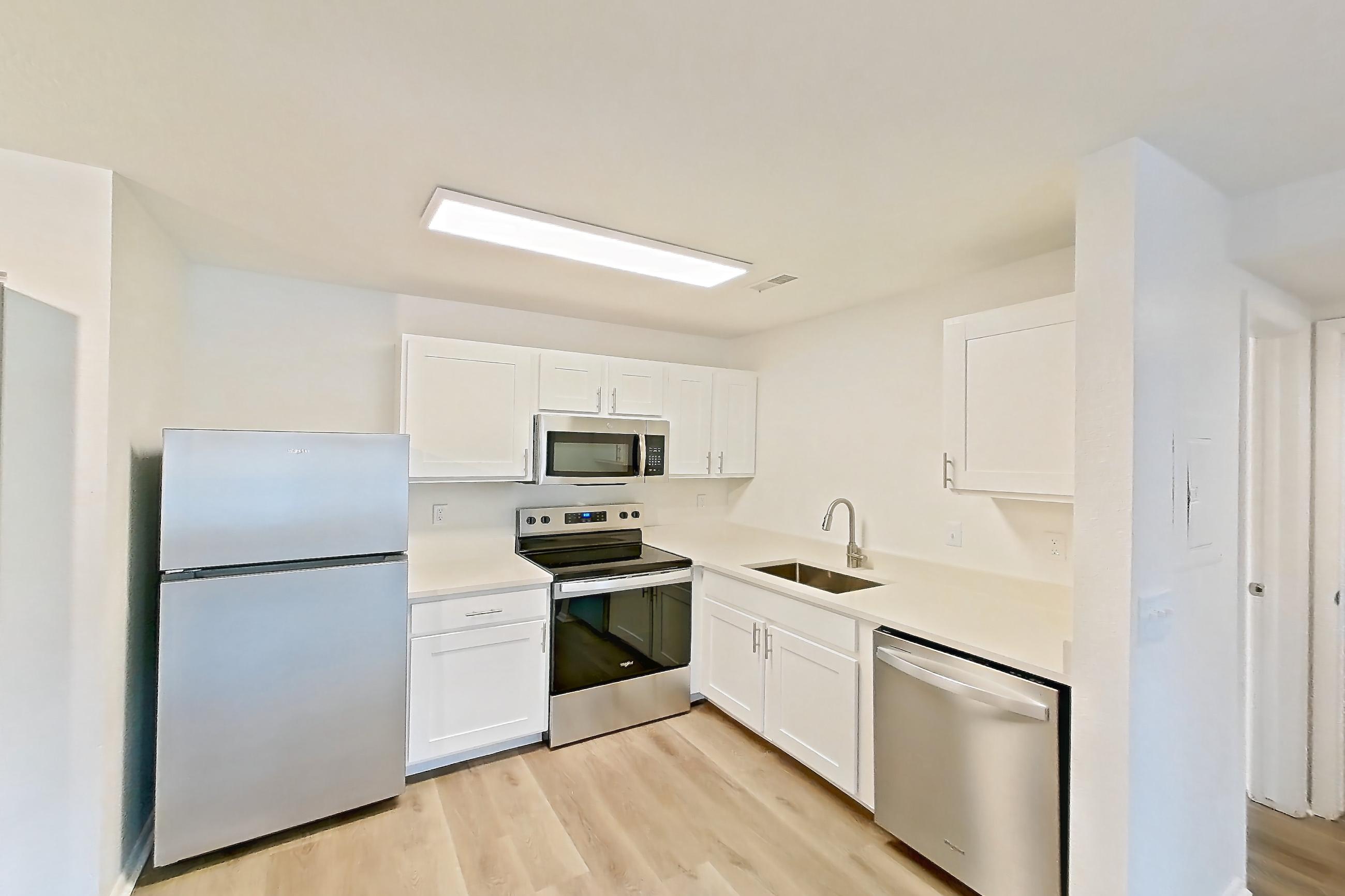 Dining room with dishwasher, electric range, in-unit laundry, light countertops, light wood-finish flooring, oven/range, refrigerator, and stainless steel appliances, Apartment 06P at Stillwater
