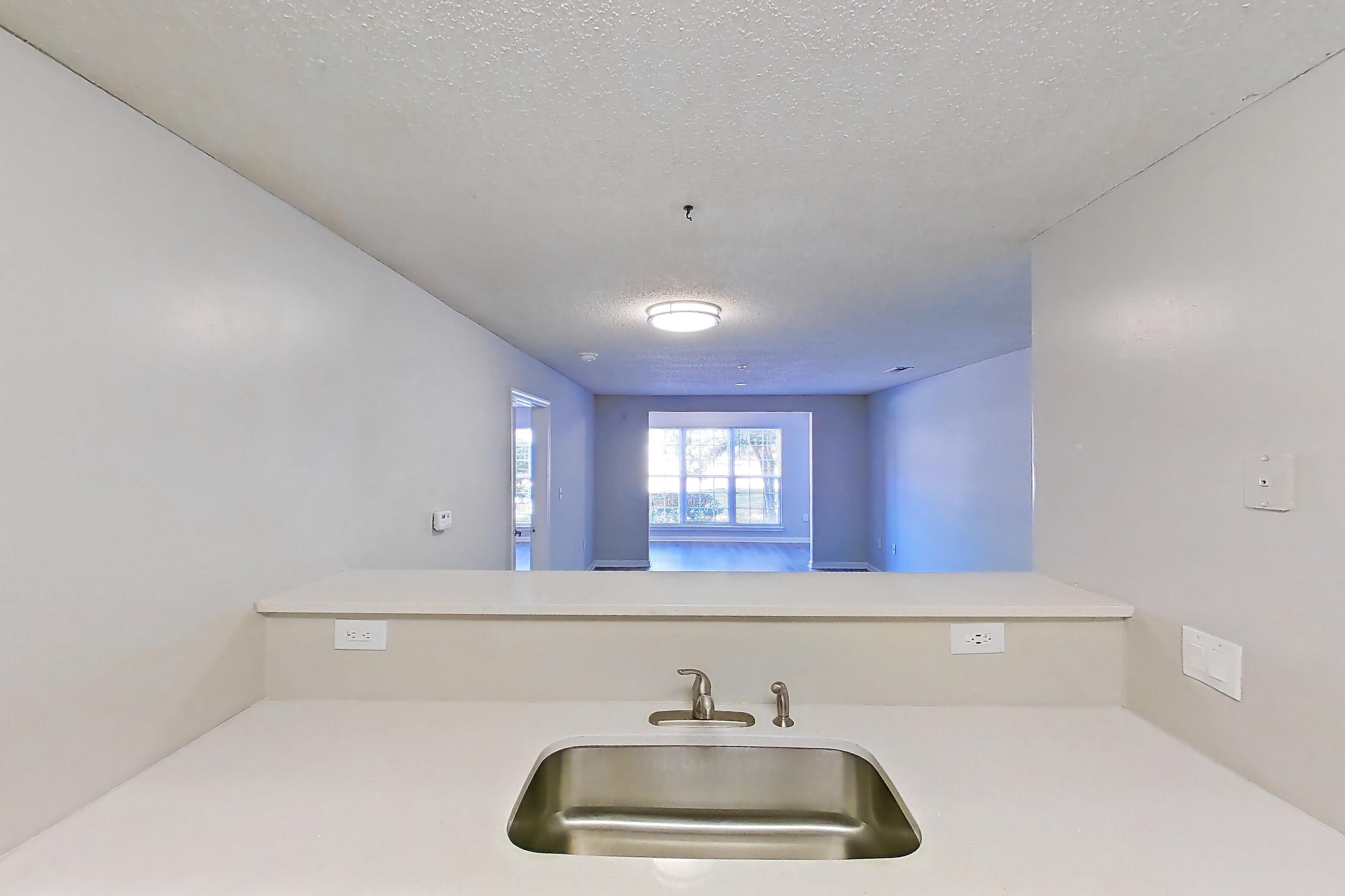 Kitchen with black appliances, dishwasher, electric range, light countertops, light stone countertops, light wood-finish flooring, oven/range, and refrigerator, Apartment 6810-1F at Ashford Place