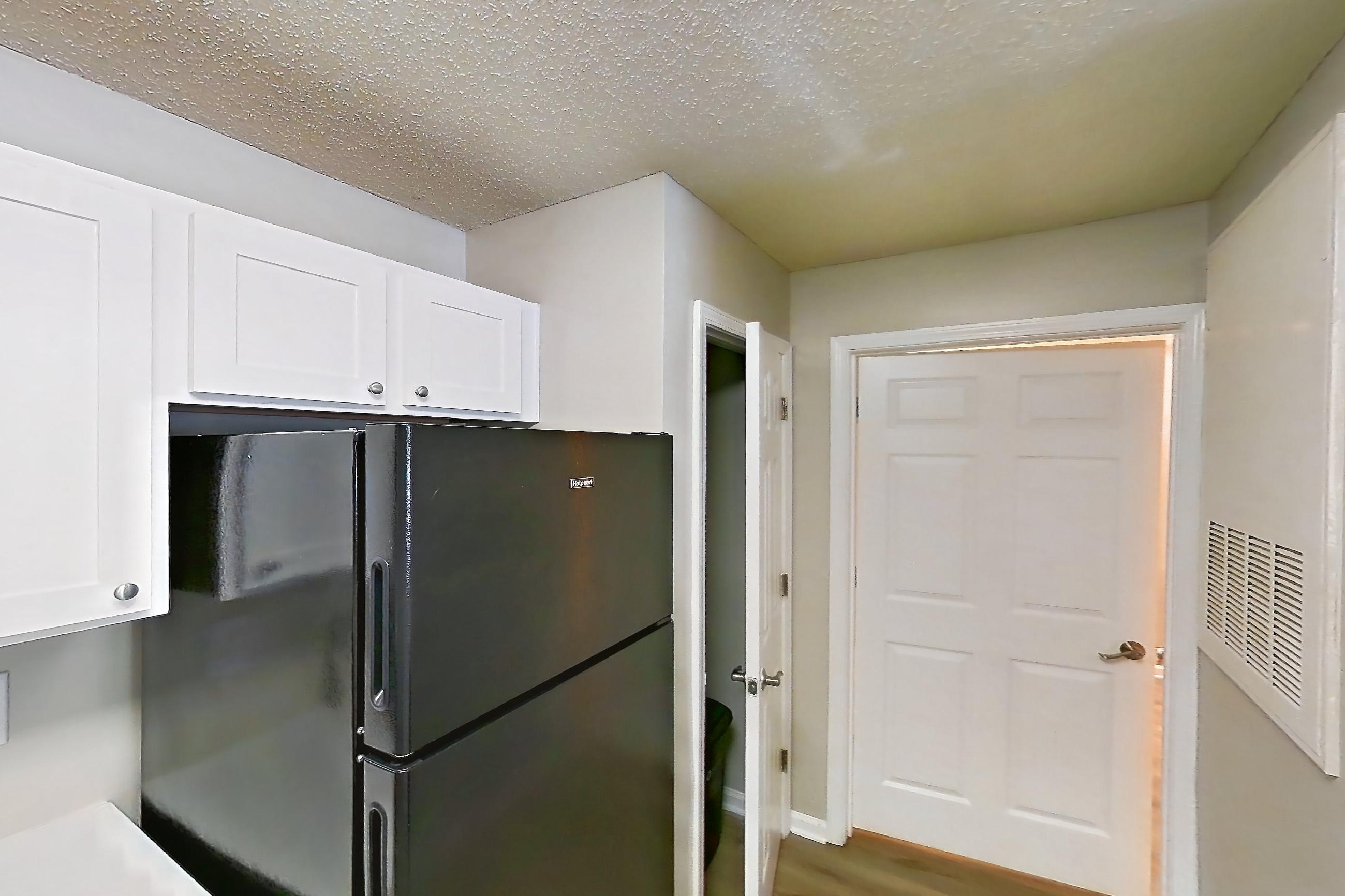 Kitchen with black appliances, dishwasher, electric range, light countertops, light stone countertops, light wood-finish flooring, oven/range, and refrigerator, Apartment 6810-1F at Ashford Place