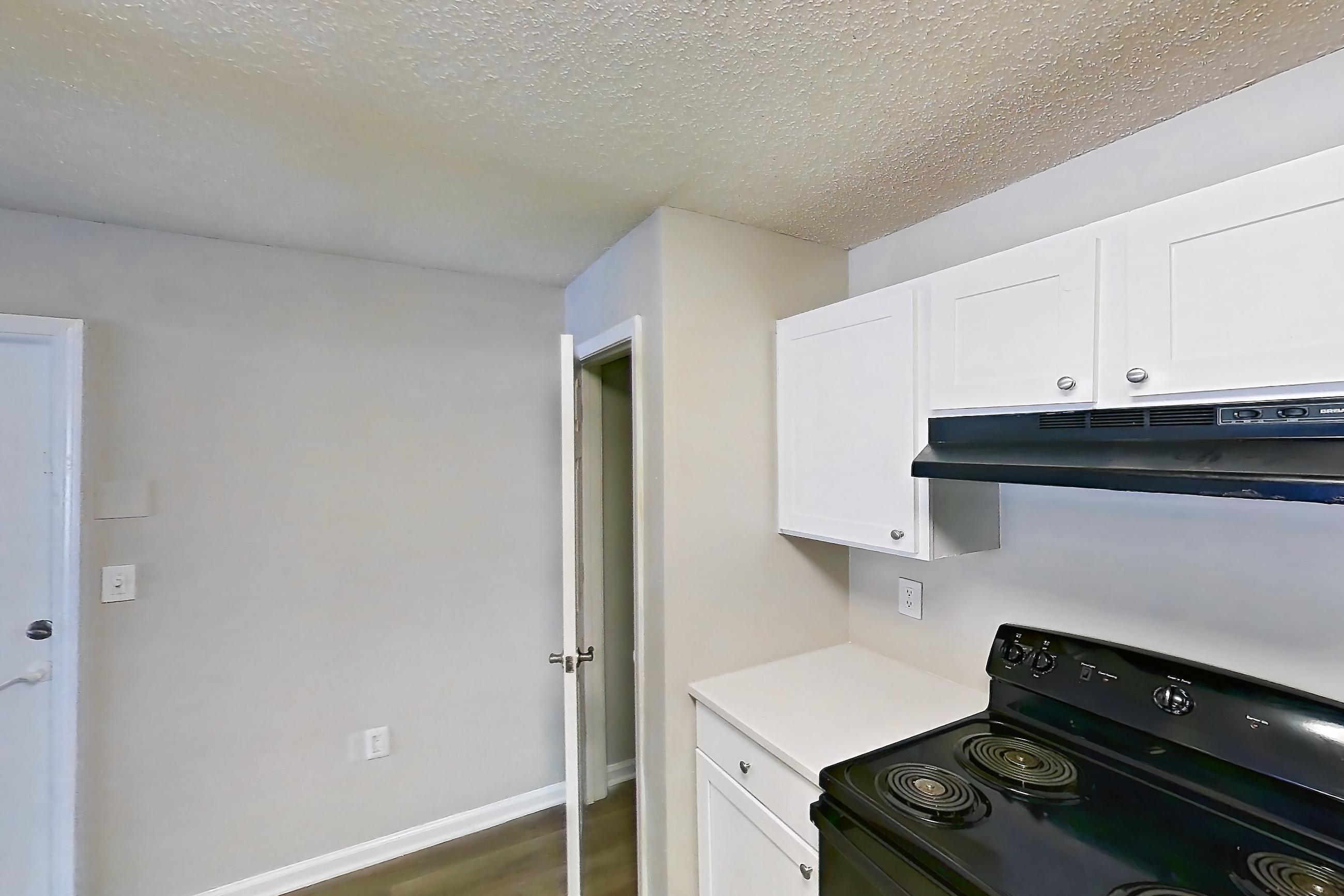 Kitchen with black appliances, dishwasher, electric range, light countertops, light stone countertops, light wood-finish flooring, oven/range, and refrigerator, Apartment 6810-1F at Ashford Place