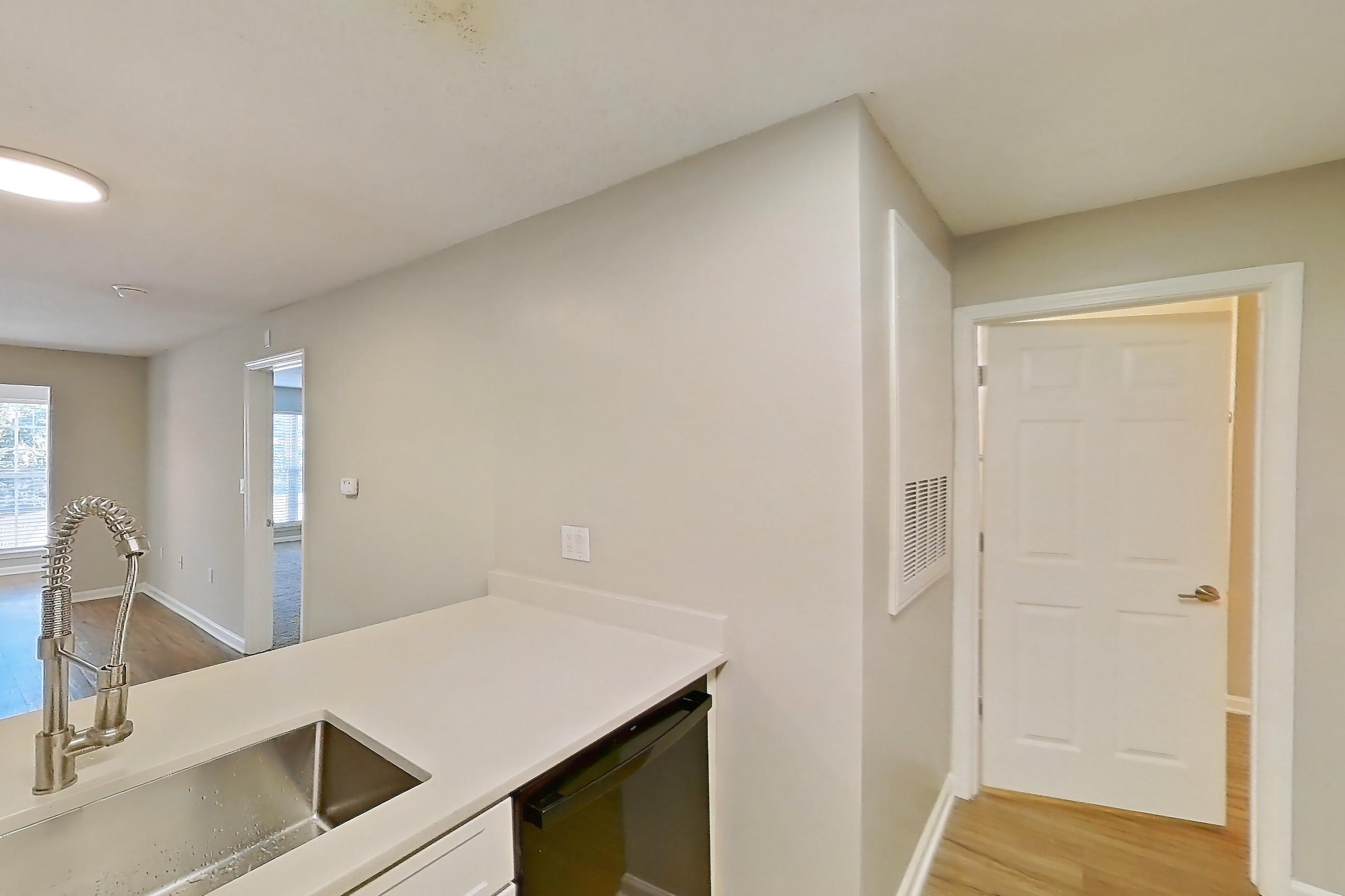 Kitchen with black appliances, dishwasher, electric range, light countertops, light wood-finish flooring, oven/range, range hood, refrigerator, and stainless steel appliances, Apartment 6425-3C at Ashford Place