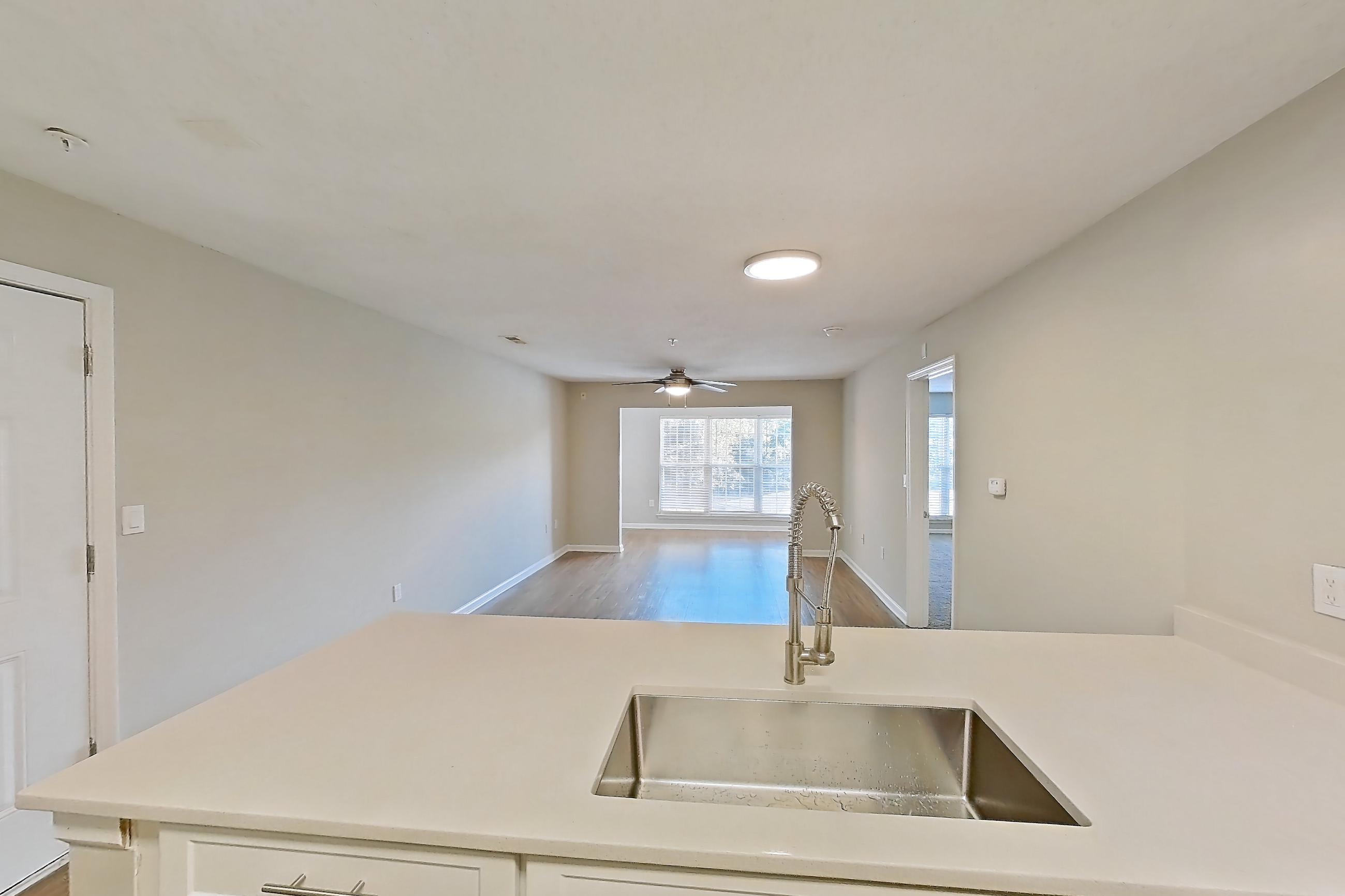 Kitchen with black appliances, dishwasher, electric range, light countertops, light wood-finish flooring, oven/range, range hood, refrigerator, and stainless steel appliances, Apartment 6425-3C at Ashford Place