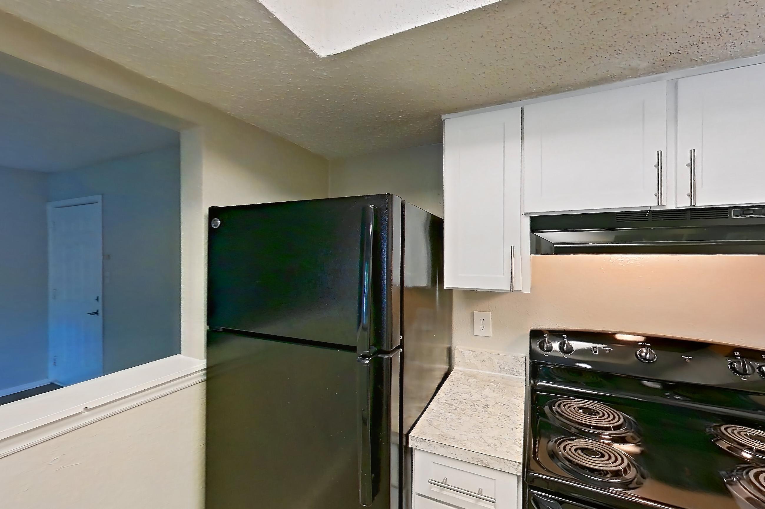 Kitchen with black appliances, dishwasher, electric range, light countertops, light wood-finish flooring, oven/range, range hood, and refrigerator, Apartment 0616 at Beacon Hill