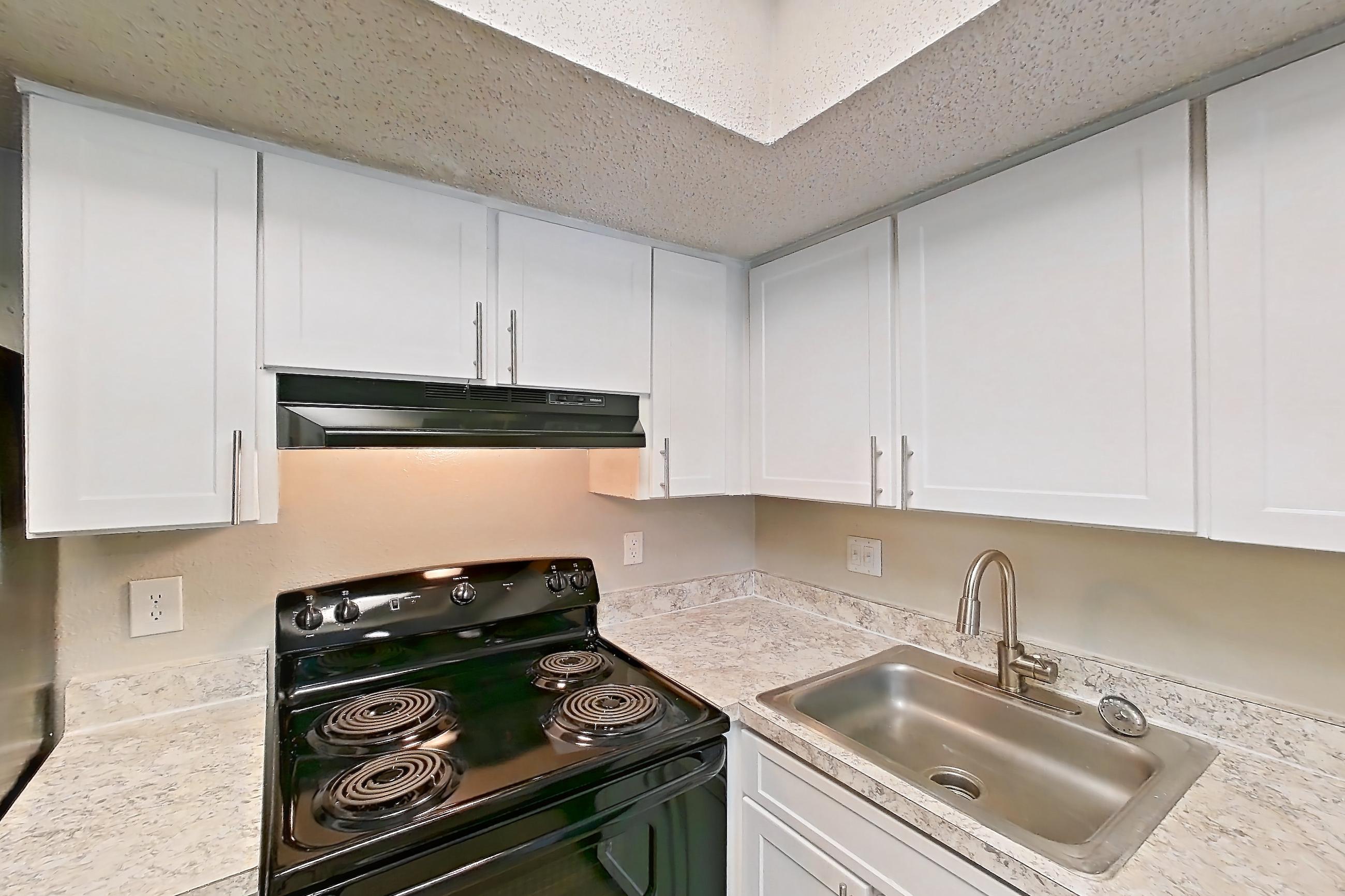Kitchen with black appliances, dishwasher, electric range, light countertops, light wood-finish flooring, oven/range, range hood, and refrigerator, Apartment 0616 at Beacon Hill
