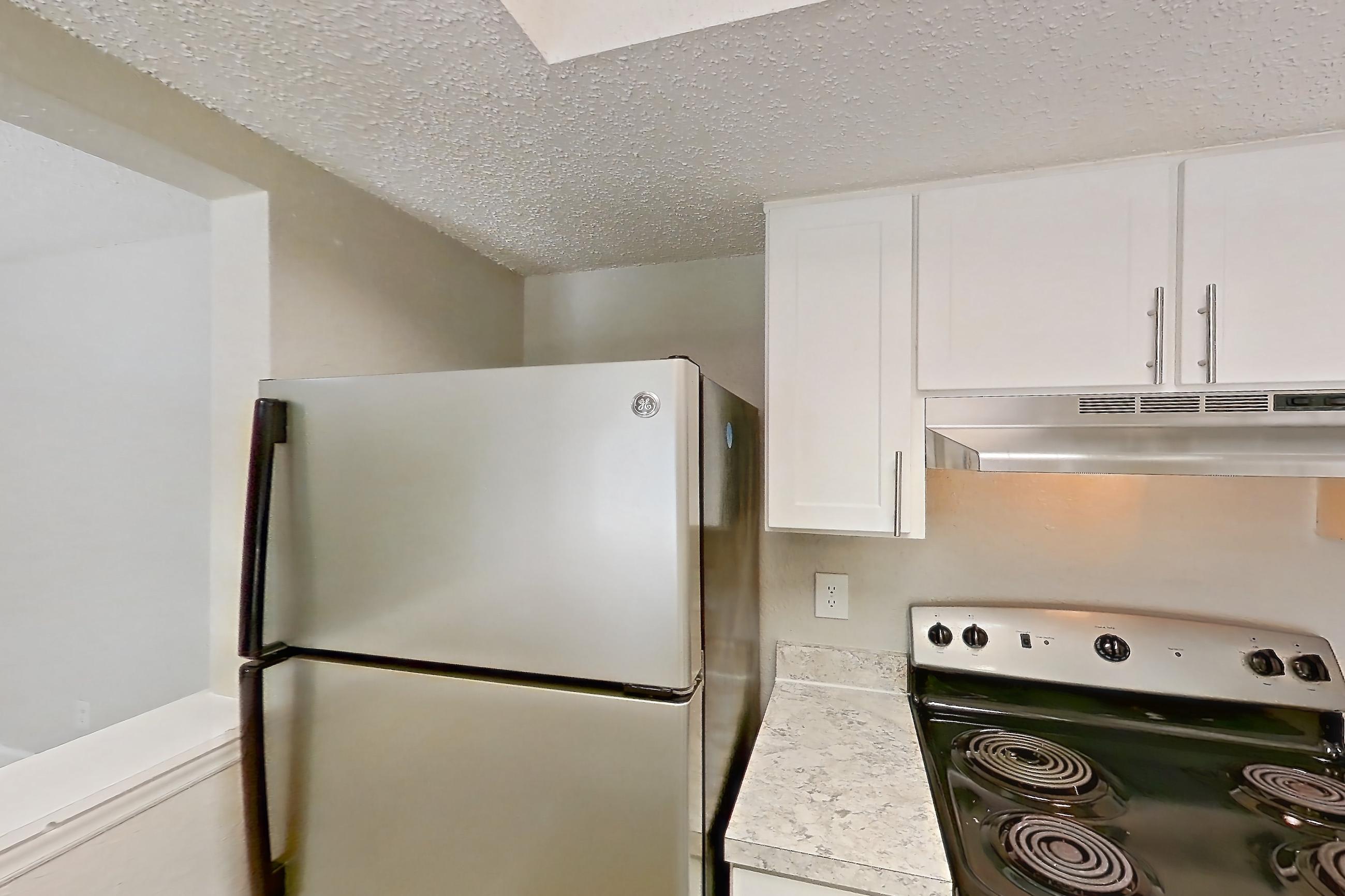 Kitchen with dishwasher, electric range, light countertops, light wood-finish flooring, oven/range, refrigerator, and stainless steel appliances, Apartment 0610 at Beacon Hill