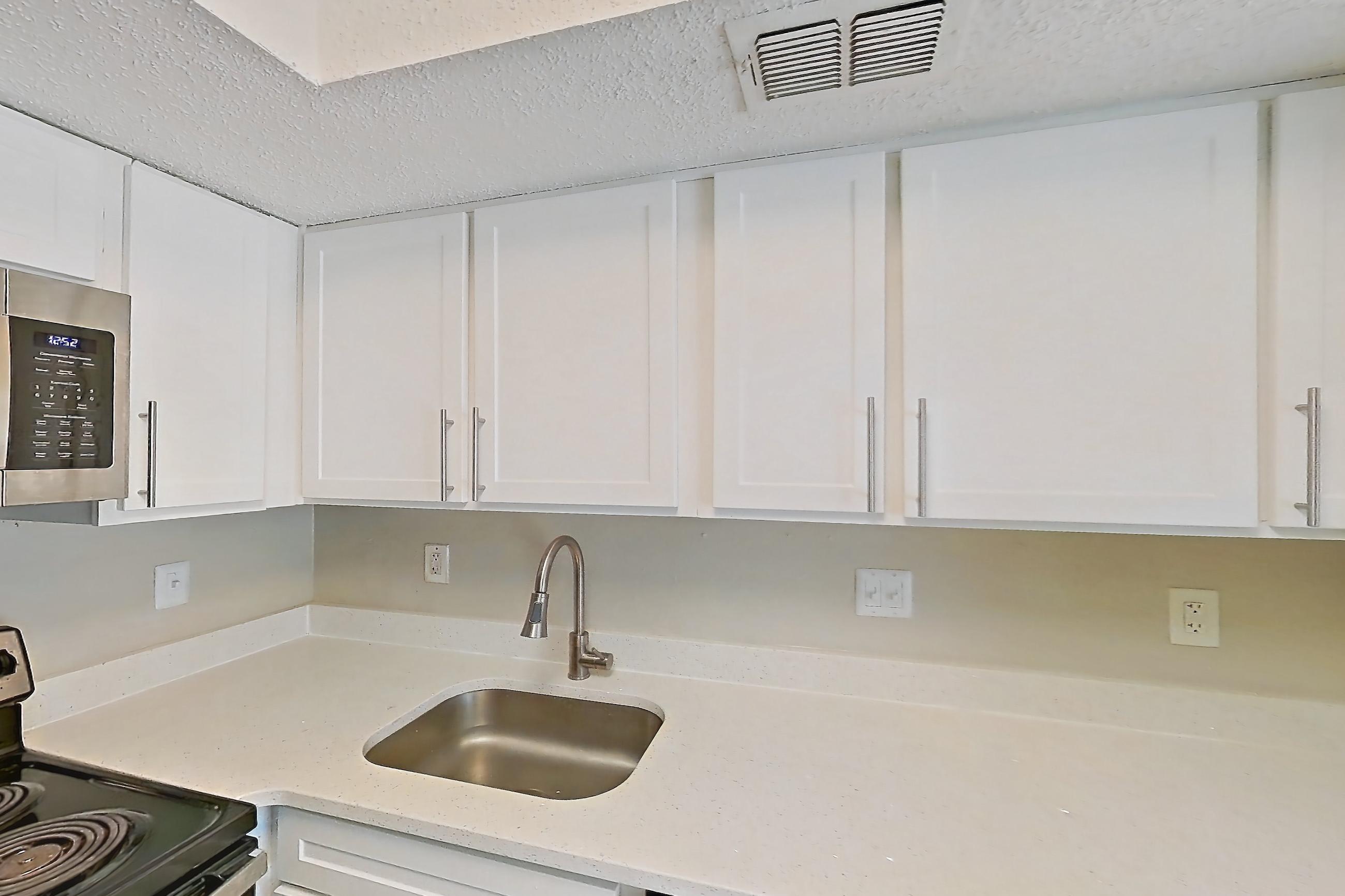 Kitchen with dishwasher, electric range, light countertops, light stone countertops, light wood-finish flooring, microwave, oven/range, range hood, refrigerator, and stainless steel appliances, Apartment 1102 at Beacon Hill