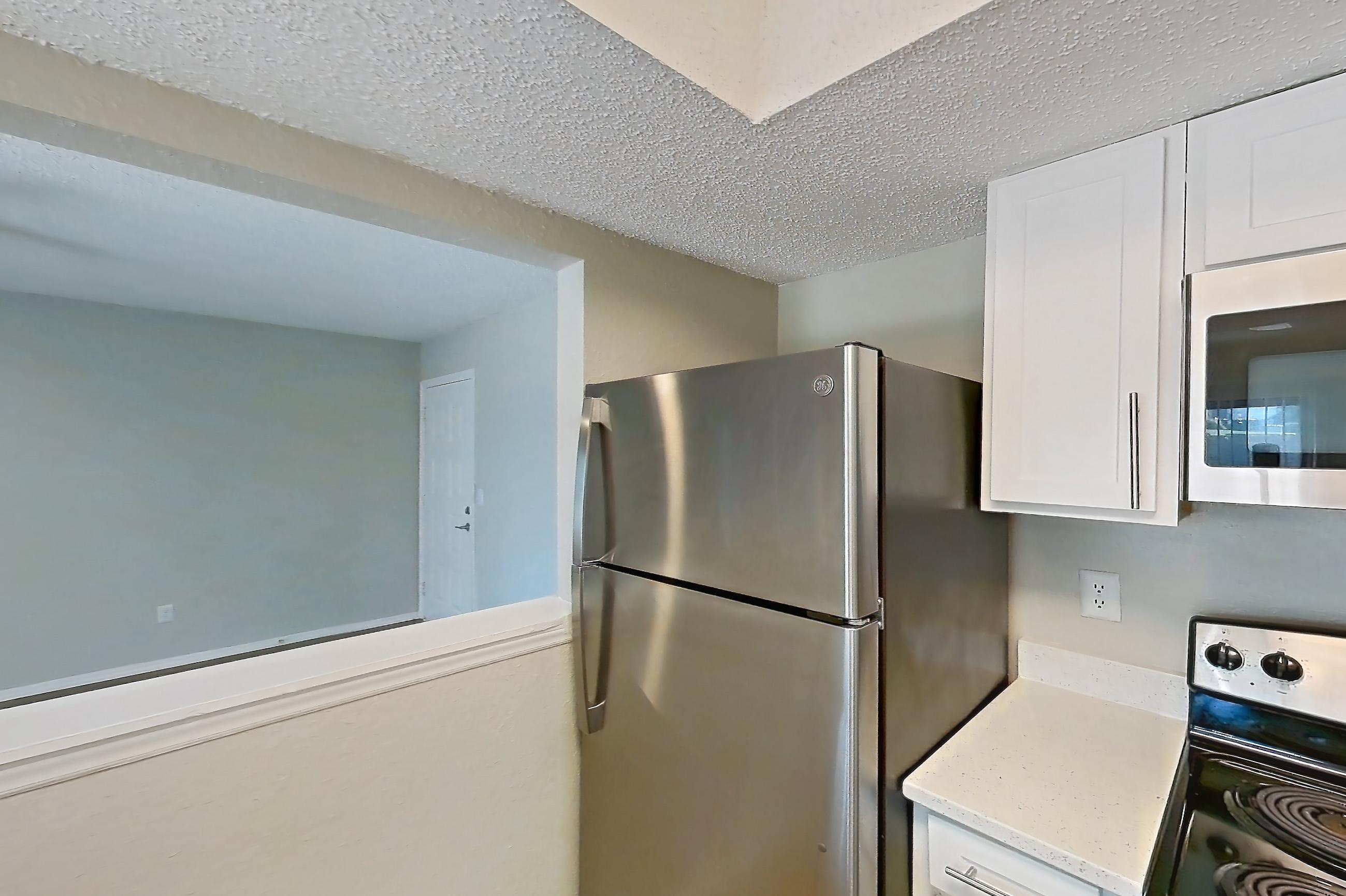 Kitchen with dishwasher, electric range, light countertops, light stone countertops, light wood-finish flooring, microwave, oven/range, range hood, refrigerator, and stainless steel appliances, Apartment 1102 at Beacon Hill