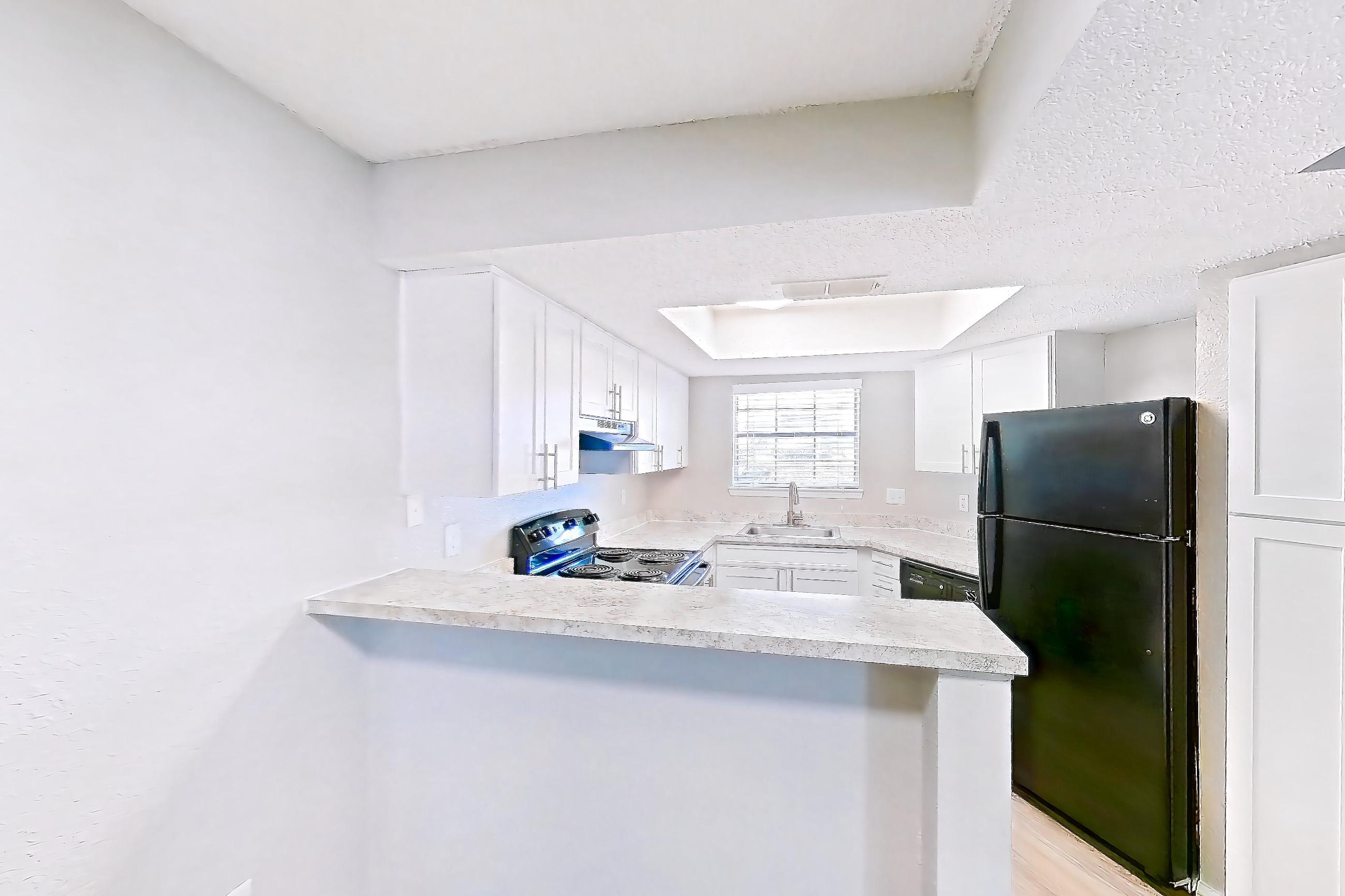 Dining room with black appliances, electric range, fireplace, light countertops, light wood-finish flooring, and oven/range, Apartment 0505 at Beacon Hill