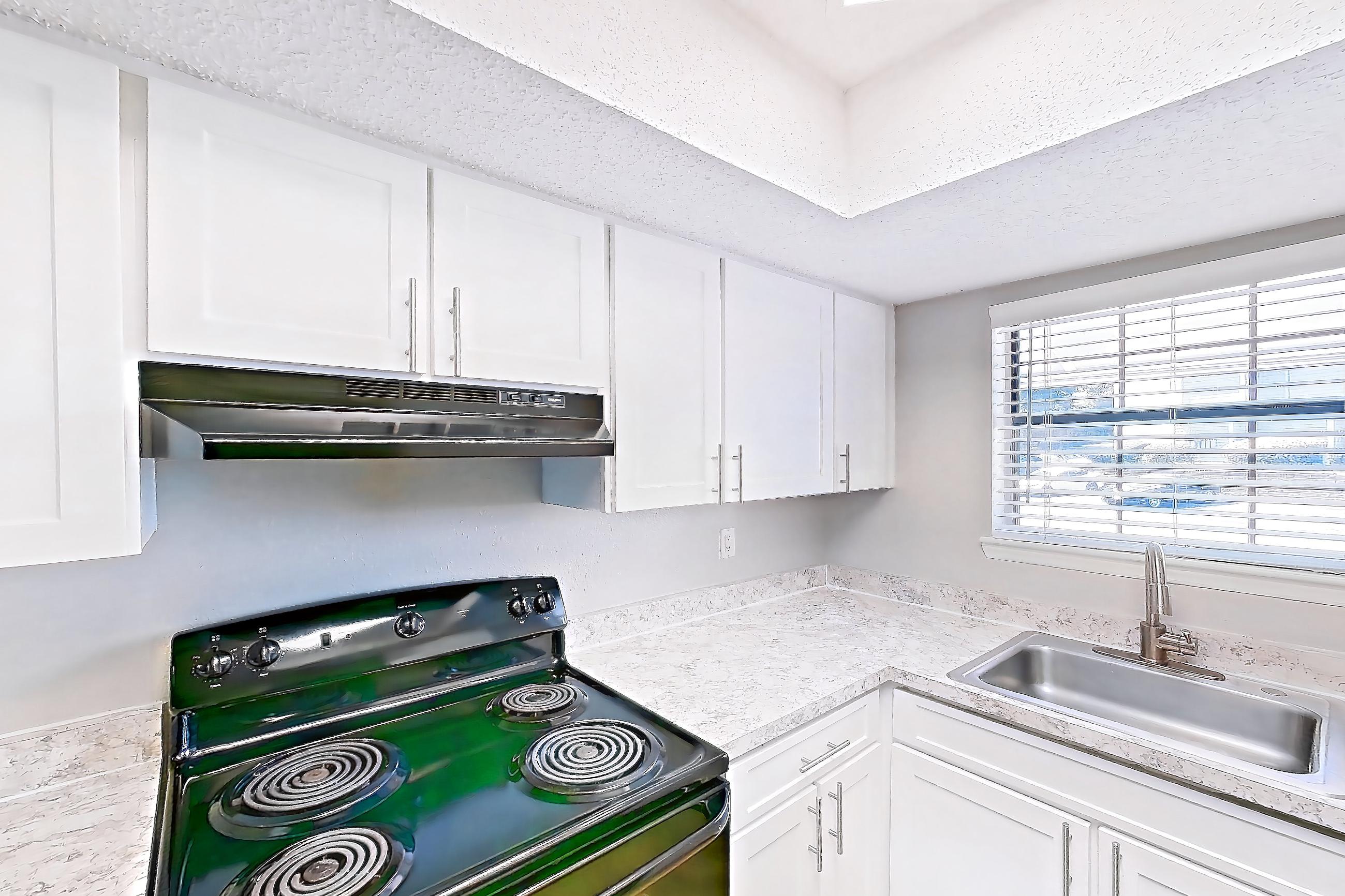 Kitchen with black appliances, dishwasher, electric range, light countertops, light wood-finish flooring, oven/range, refrigerator, and stainless steel appliances, Apartment 0505 at Beacon Hill