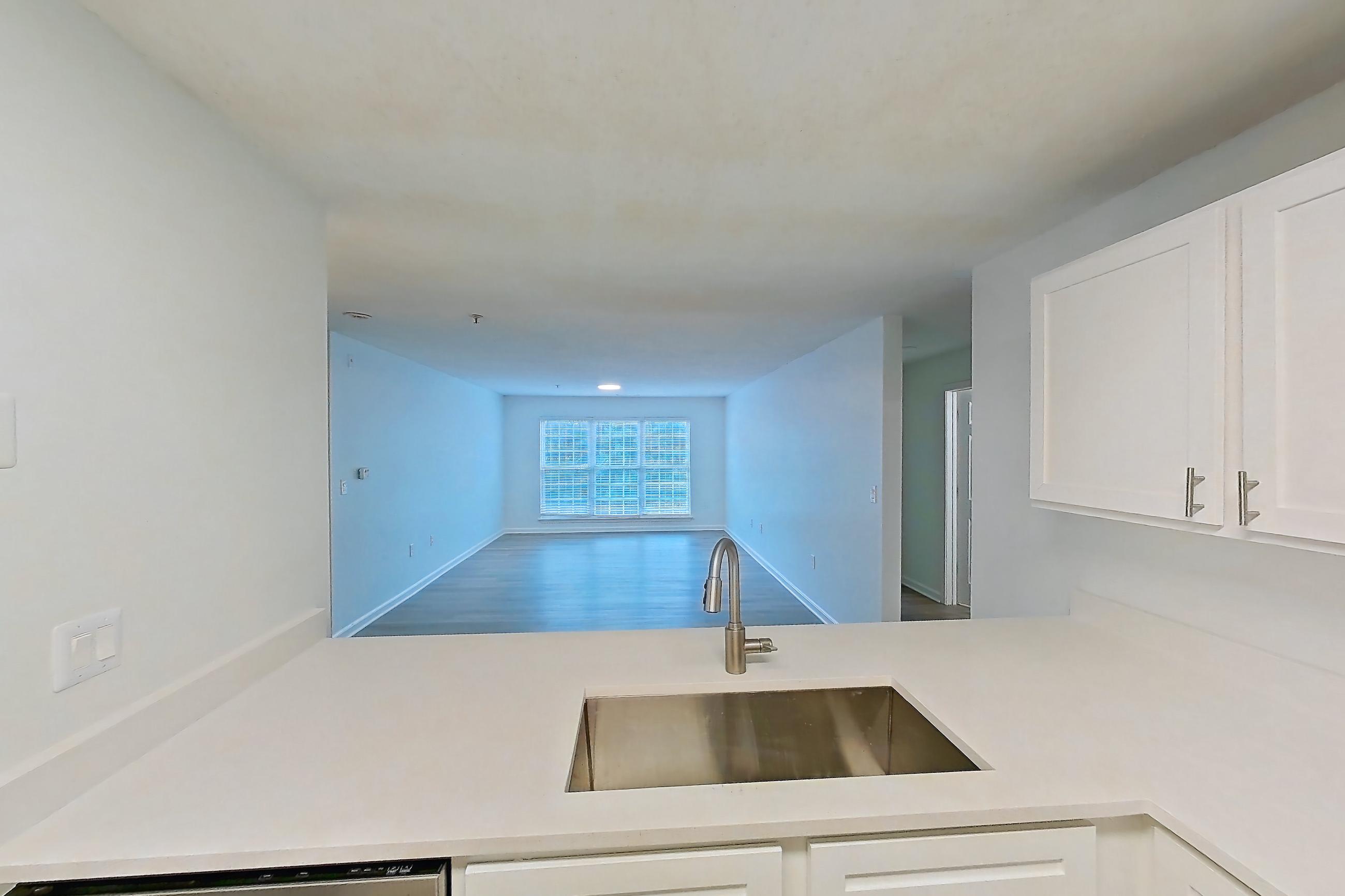 Kitchen with black appliances, dishwasher, electric range, light countertops, light stone countertops, light wood-finish flooring, microwave, oven/range, and stainless steel appliances, Apartment 6415-3H at Ashford Place