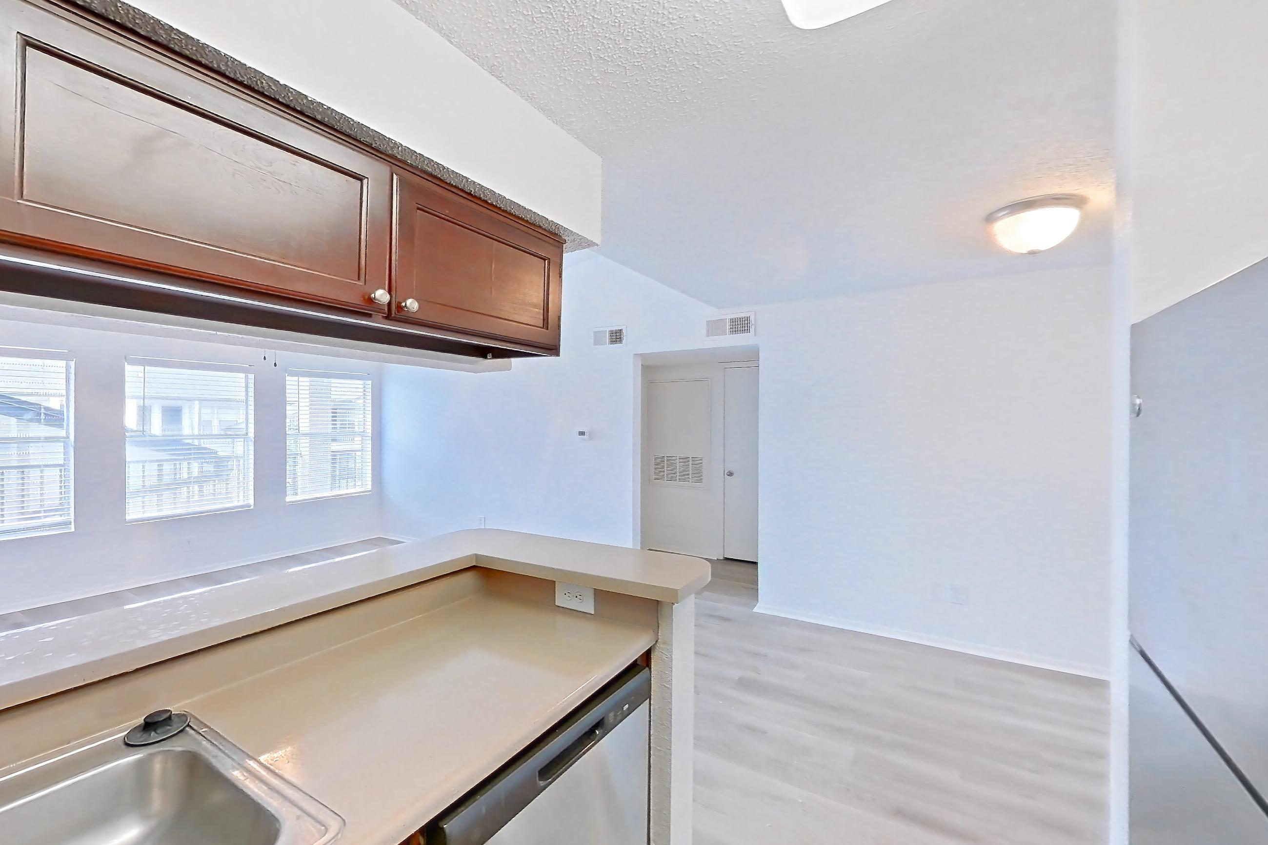 Kitchen with dishwasher, electric range, light countertops, light wood-finish flooring, oven/range, range hood, refrigerator, and stainless steel appliances, Apartment 10-0615 at Brookwood Club