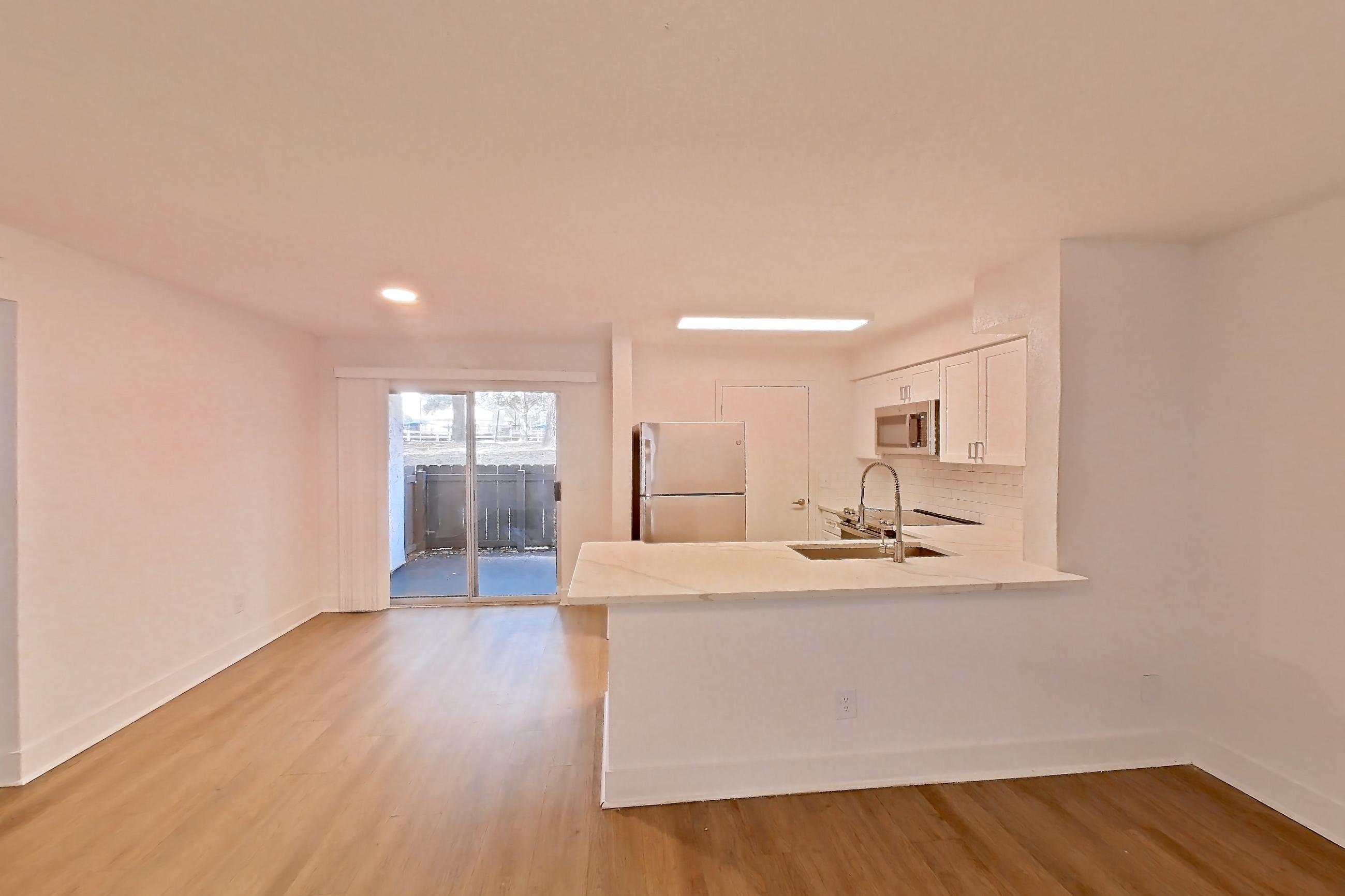 Living room with light wood-finish flooring, refrigerator, and white appliances, Apartment 10-1203 at Brookwood Club