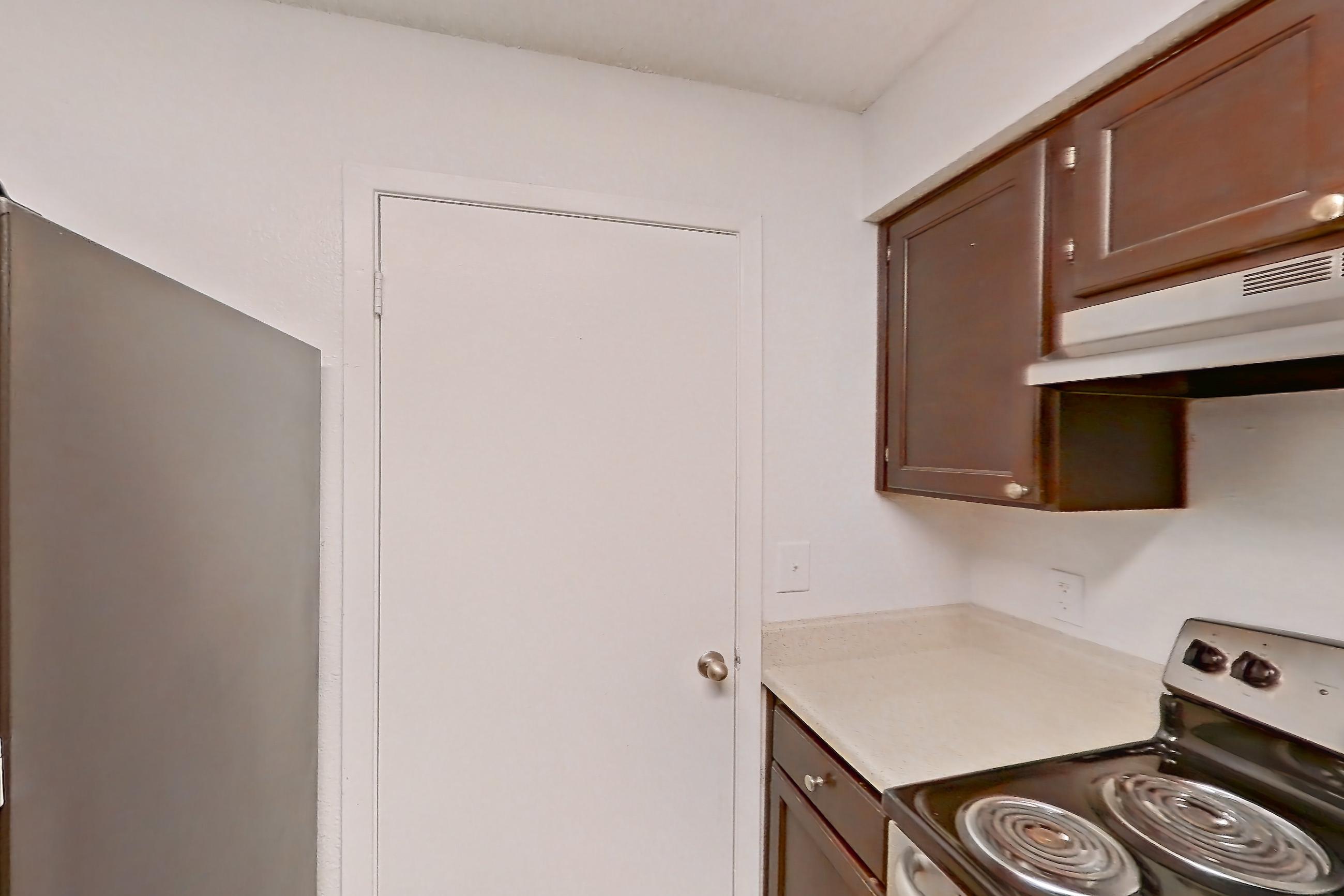 Kitchen with dishwasher, electric range, light countertops, light wood-finish flooring, oven/range, range hood, refrigerator, and stainless steel appliances, Apartment 10-1102 at Brookwood Club