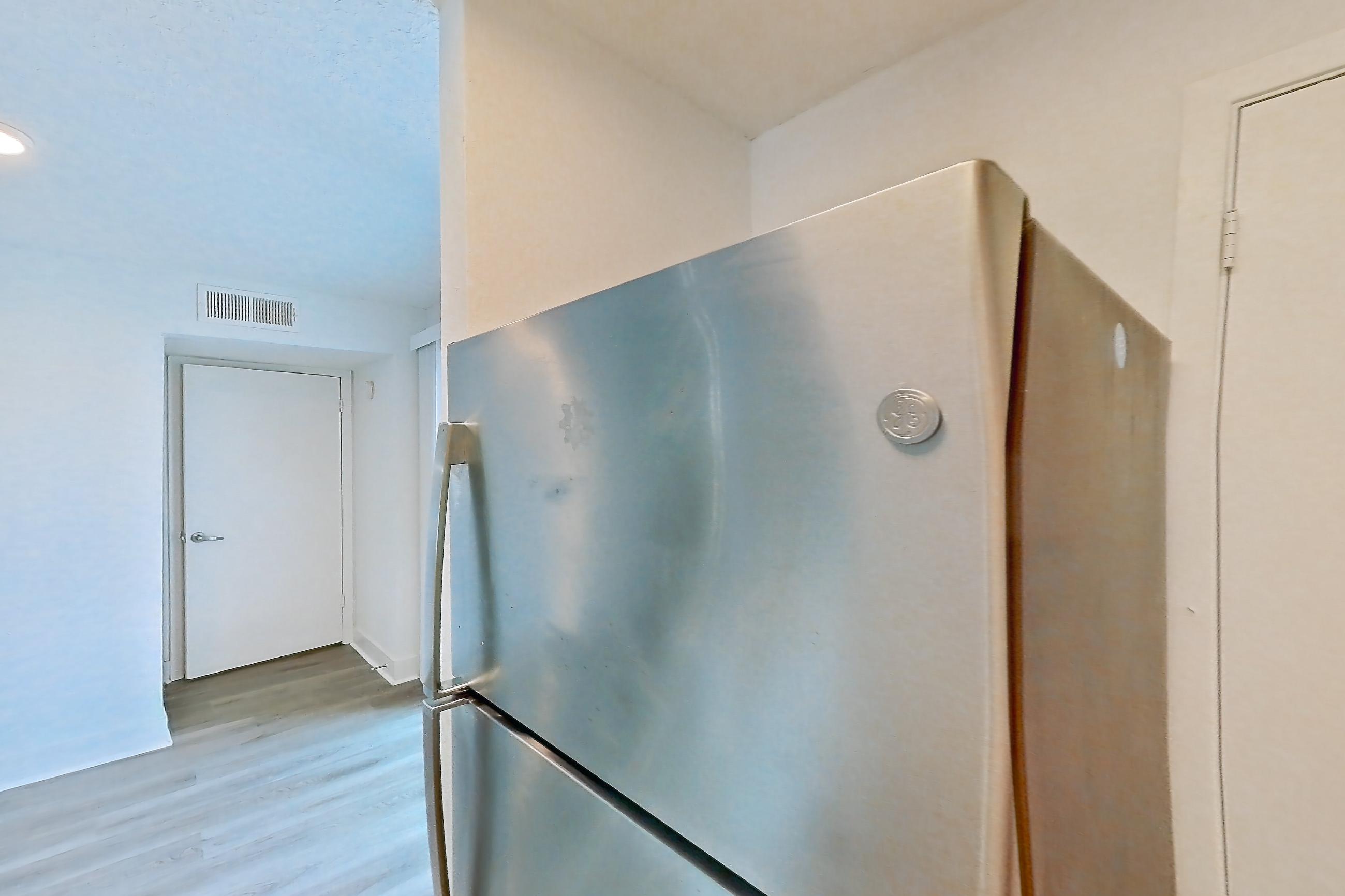 Kitchen with dishwasher, electric range, light countertops, light stone countertops, light wood-finish flooring, microwave, oven/range, refrigerator, and stainless steel appliances, Apartment 20-0517 at Brookwood Club