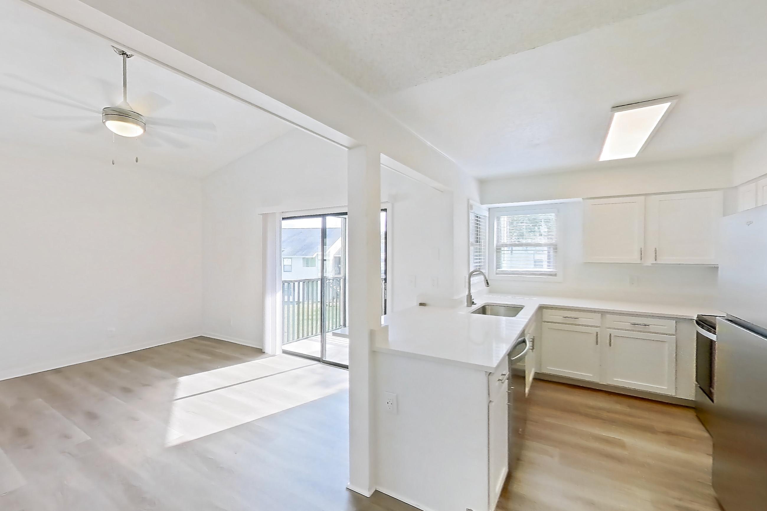 Dining room with dishwasher, light countertops, light stone countertops, light wood-finish flooring, refrigerator, and stainless steel appliances, Apartment 6016GD at Oak Ramble