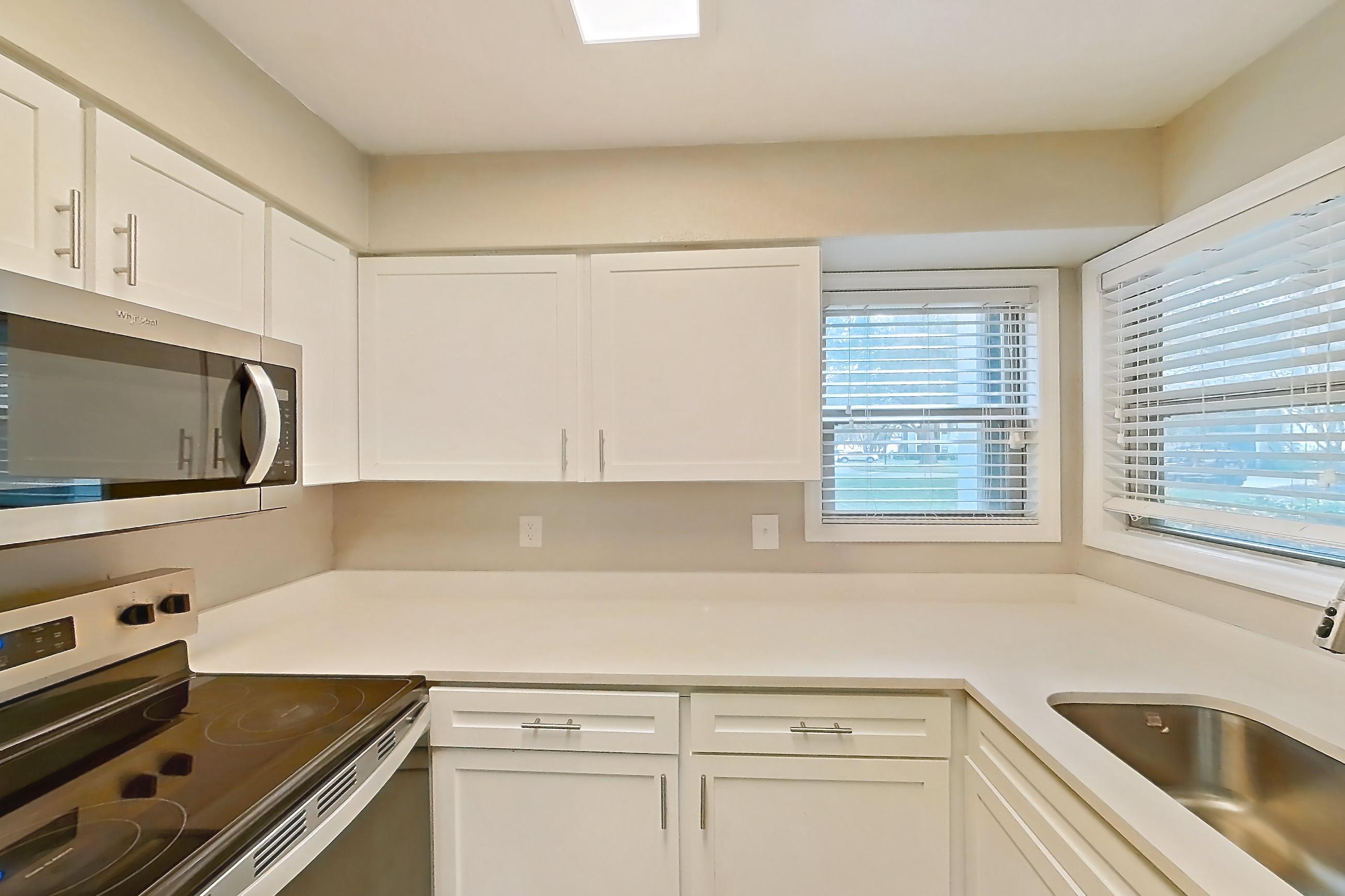 Kitchen with dishwasher, electric range, light countertops, light stone countertops, light wood-finish flooring, oven/range, refrigerator, and stainless steel appliances, Apartment 6125GD at Oak Ramble