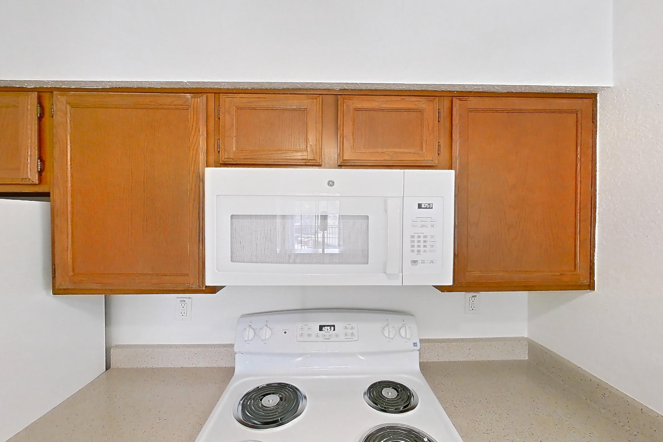 Kitchen with dishwasher, electric range, light stone countertops, light wood-finish flooring, microwave, oven/range, refrigerator, and white appliances, Apartment 4137 at Canyon Chase