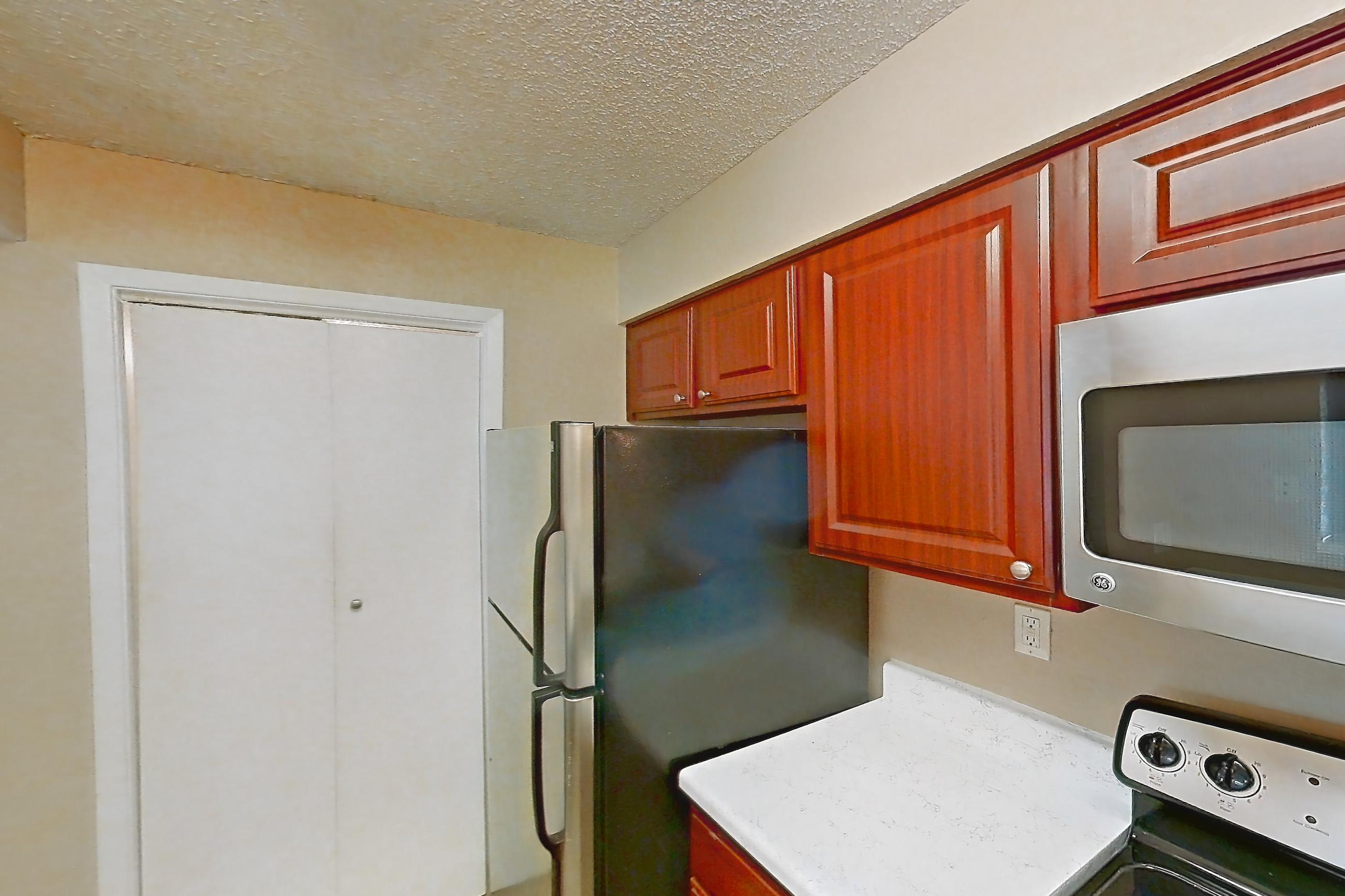 Kitchen with dishwasher, electric range, light countertops, light stone countertops, light wood-finish flooring, microwave, oven/range, refrigerator, and stainless steel appliances, Apartment 3527 at Canyon Chase