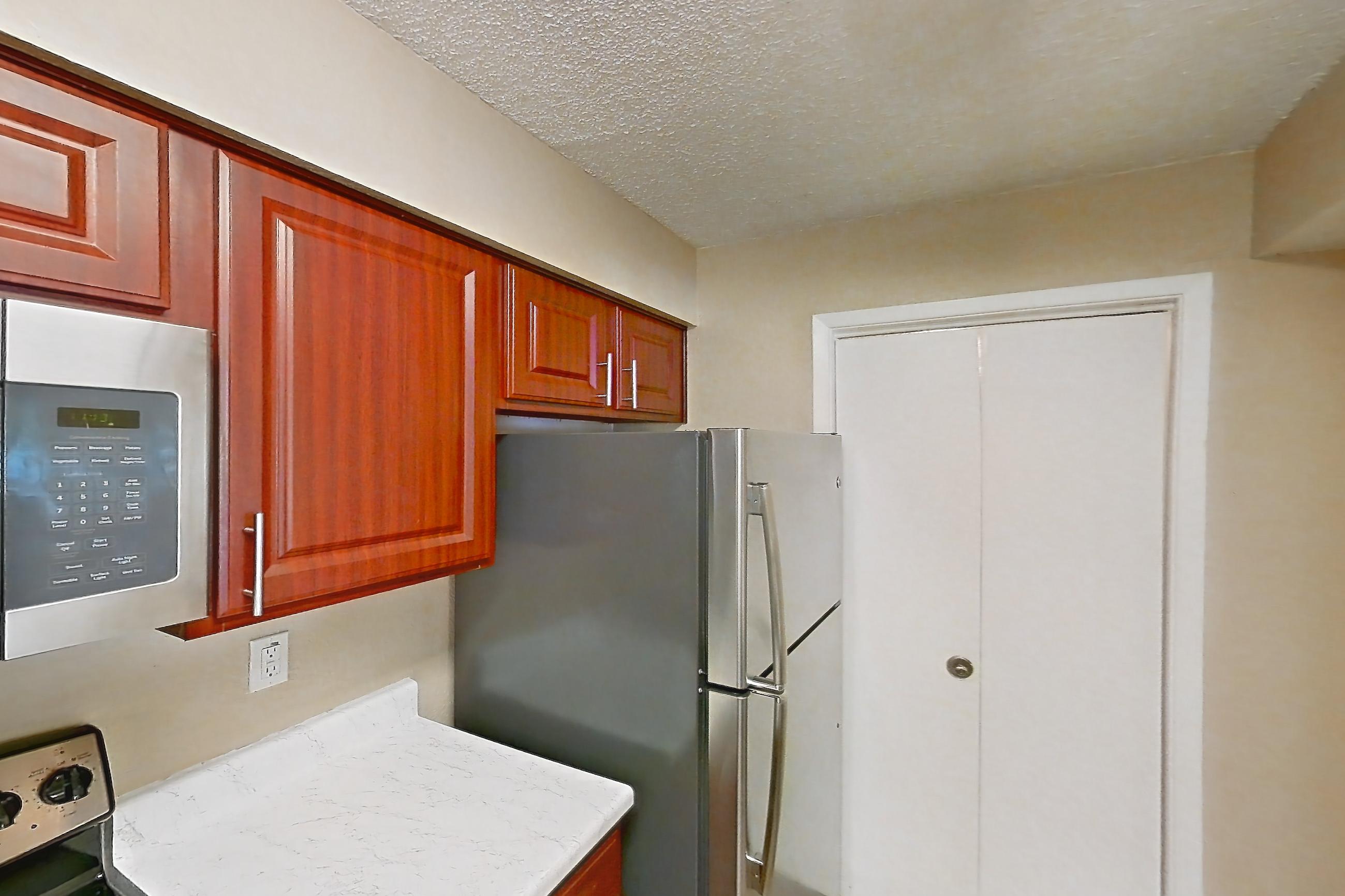 Kitchen with dishwasher, electric range, light countertops, light stone countertops, light wood-finish flooring, microwave, oven/range, refrigerator, and stainless steel appliances, Apartment 3514 at Canyon Chase