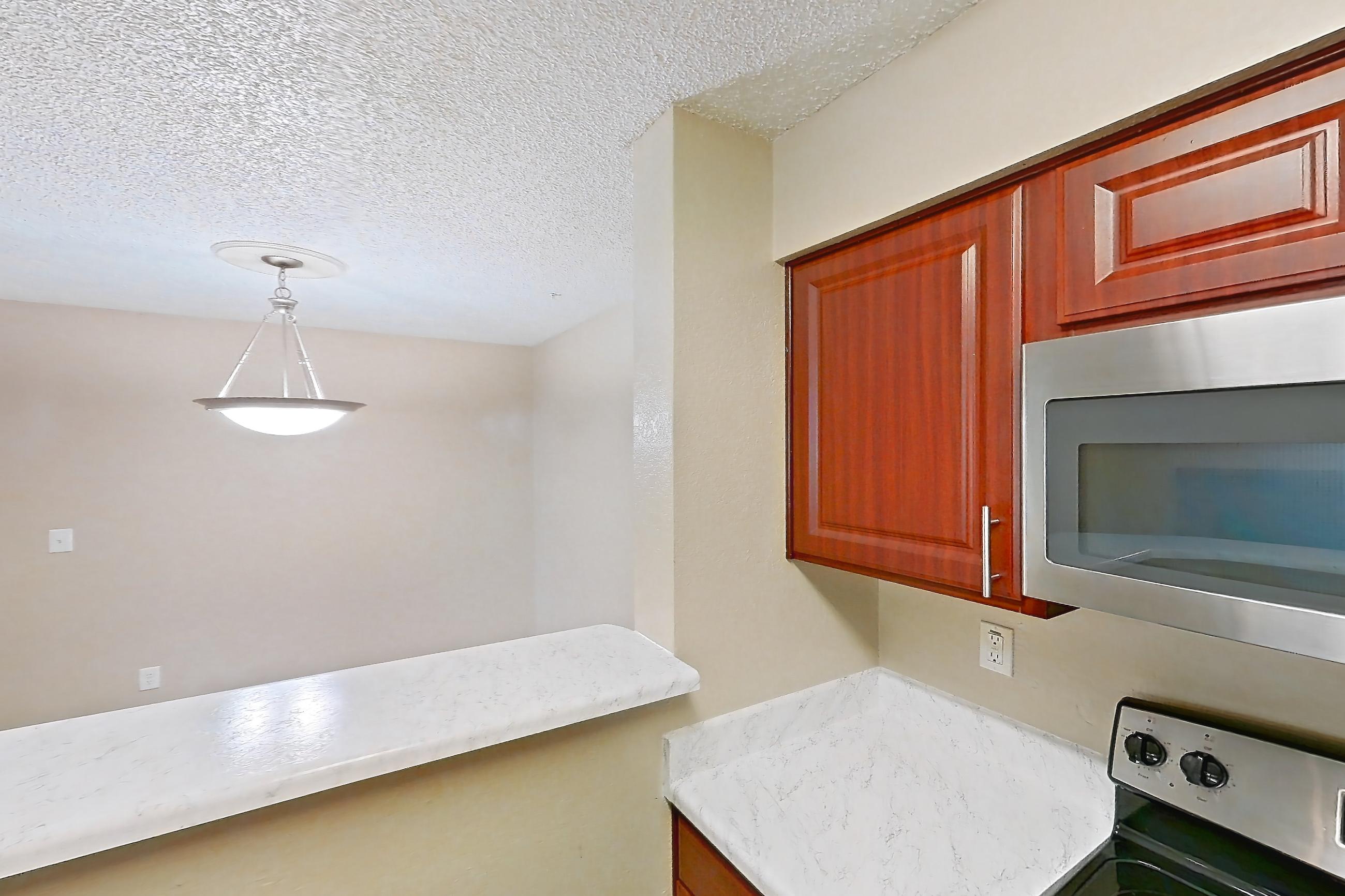 Kitchen with dishwasher, electric range, light countertops, light stone countertops, light wood-finish flooring, microwave, oven/range, refrigerator, and stainless steel appliances, Apartment 3514 at Canyon Chase