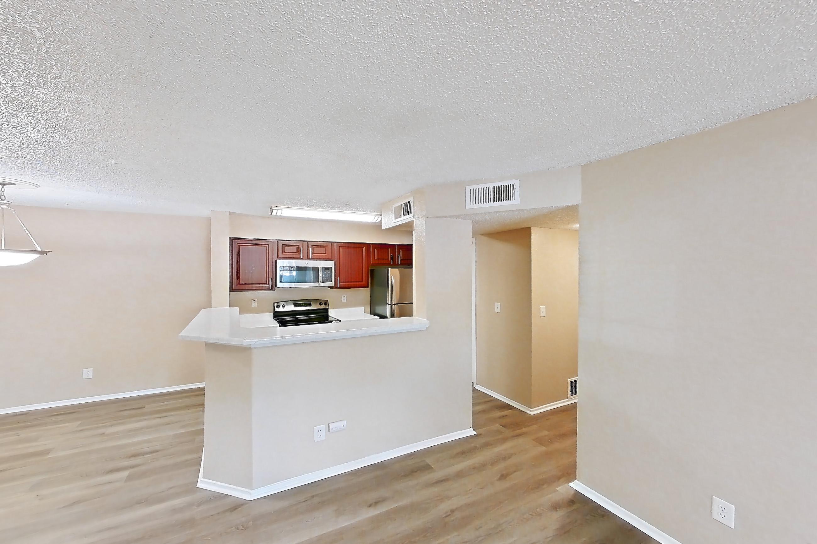 Living space with brick fireplace, electric range, fireplace, light countertops, light wood-finish flooring, oven/range, refrigerator, and stainless steel appliances, Apartment 3514 at Canyon Chase