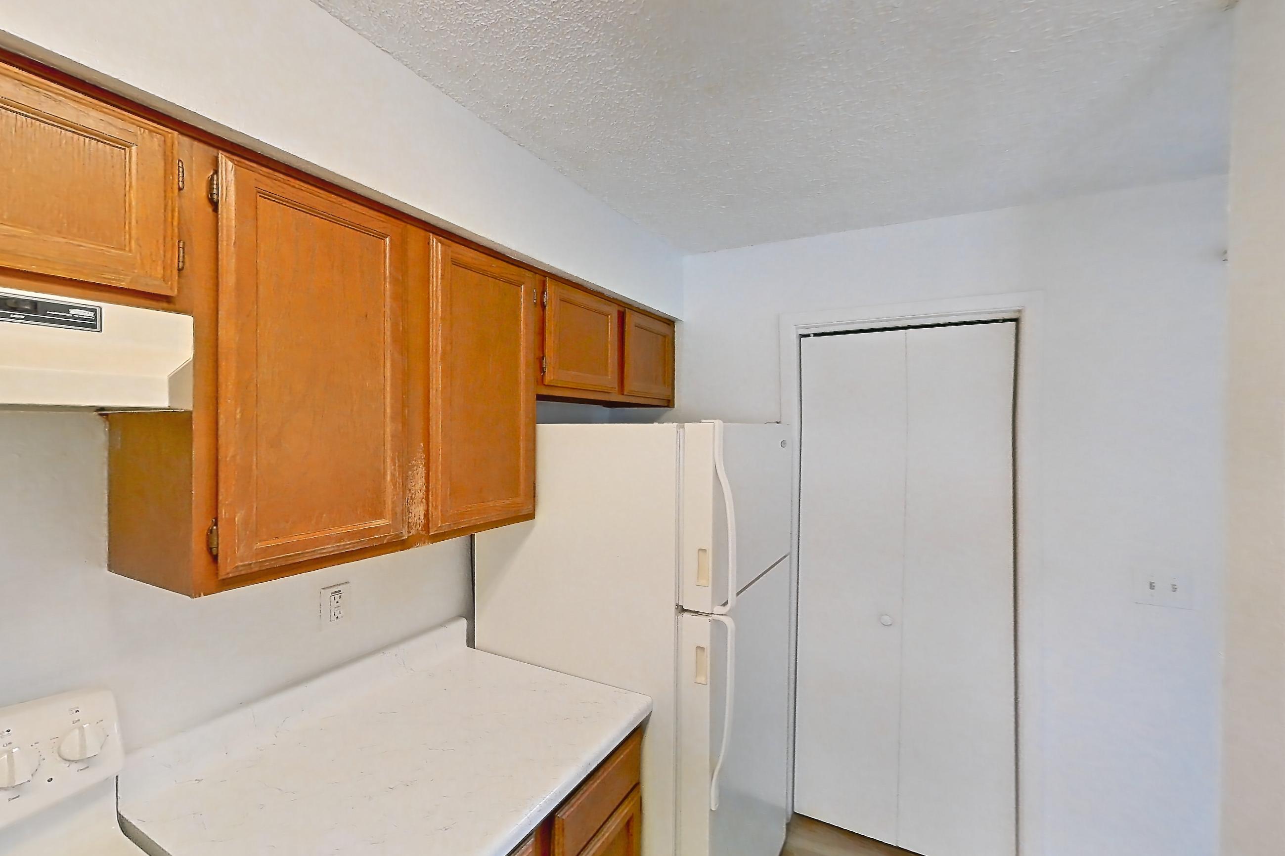 Kitchen with baseboard heating, electric range, light countertops, light stone countertops, light wood-finish flooring, oven/range, refrigerator, and white appliances, Apartment 4214 at Canyon Chase