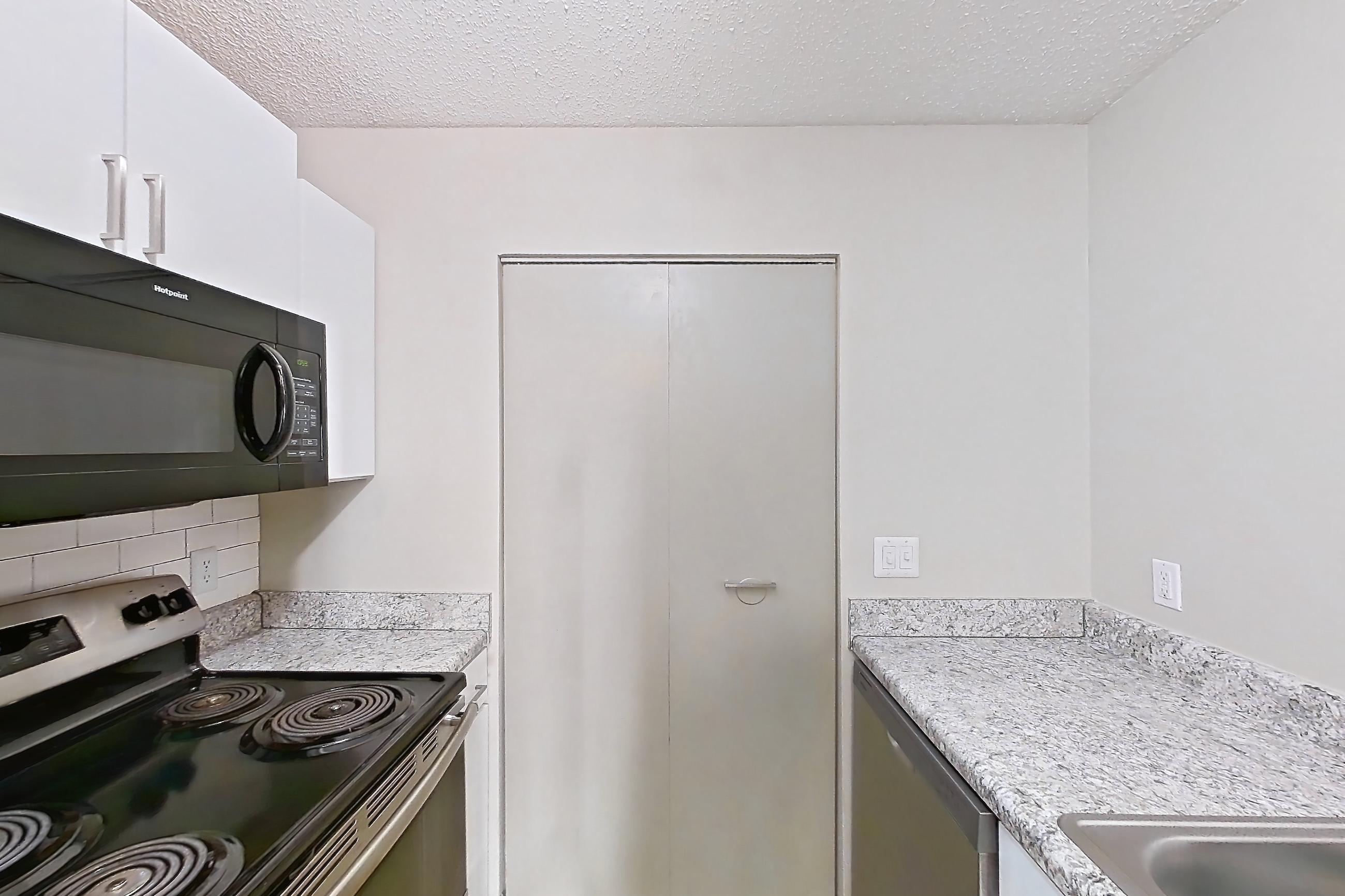 Kitchen with dishwasher, electric range, light countertops, light wood-finish flooring, oven/range, and stainless steel appliances, Apartment 61-A02 at Crosstown at Chapel Hill