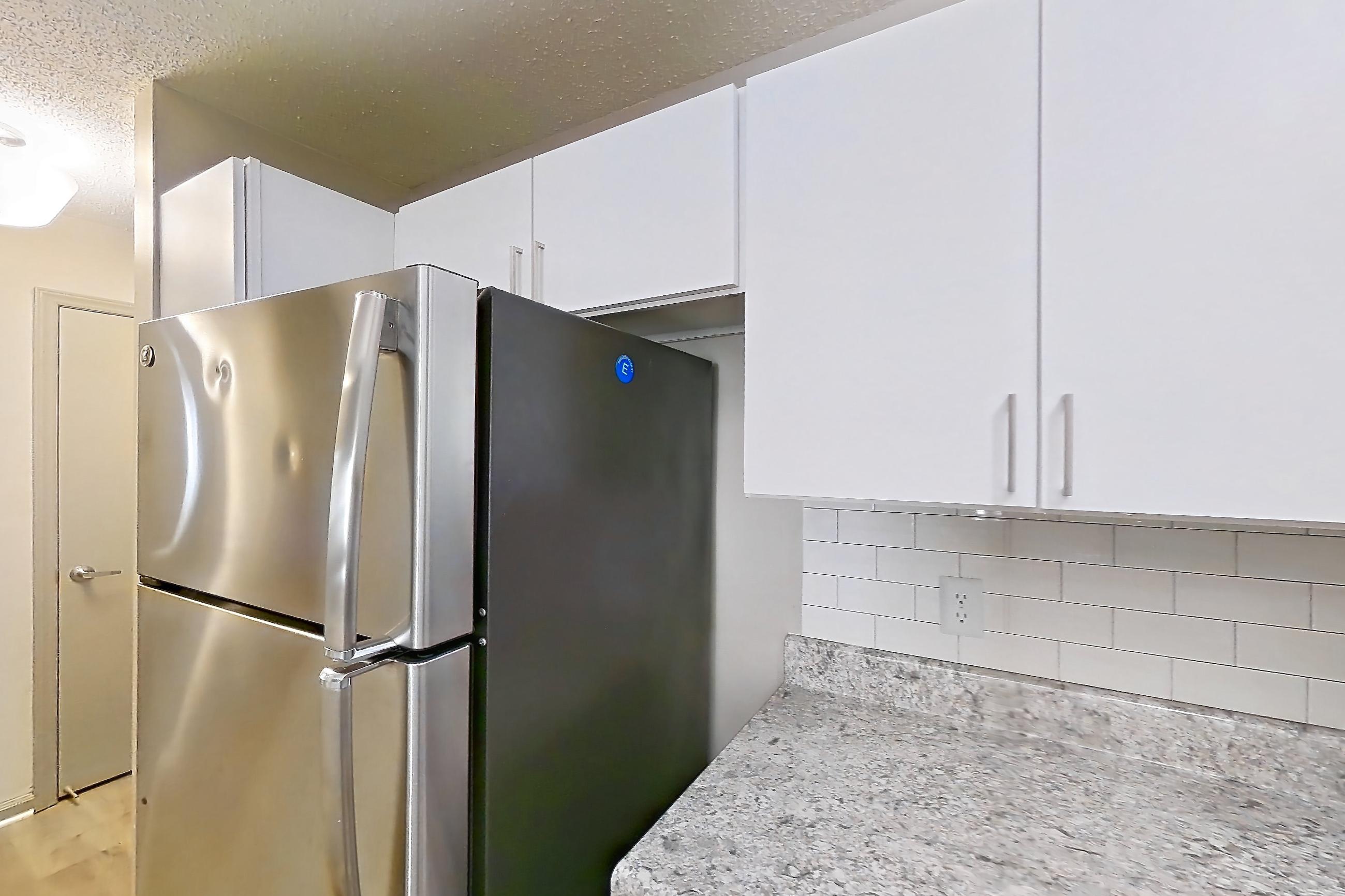 Kitchen with dishwasher, electric range, light countertops, light wood-finish flooring, oven/range, and stainless steel appliances, Apartment 61-A02 at Crosstown at Chapel Hill