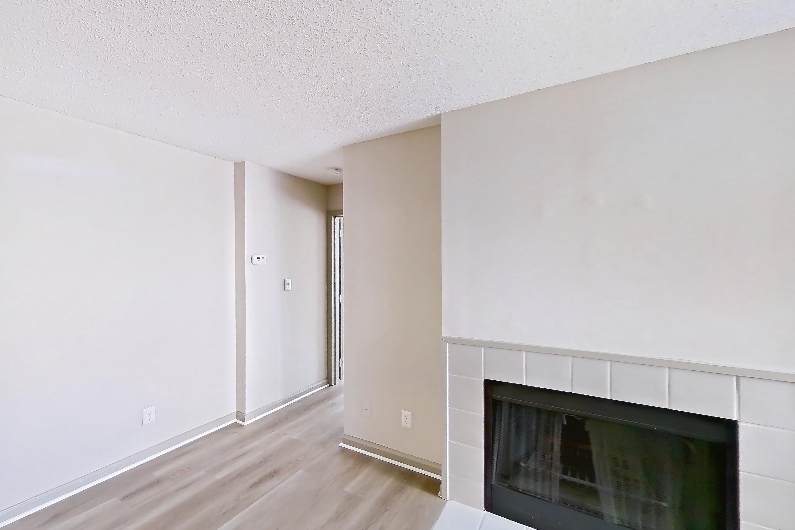 Living room with fireplace, light wood-finish flooring, and tile fireplace, Apartment 61-A02 at Crosstown at Chapel Hill