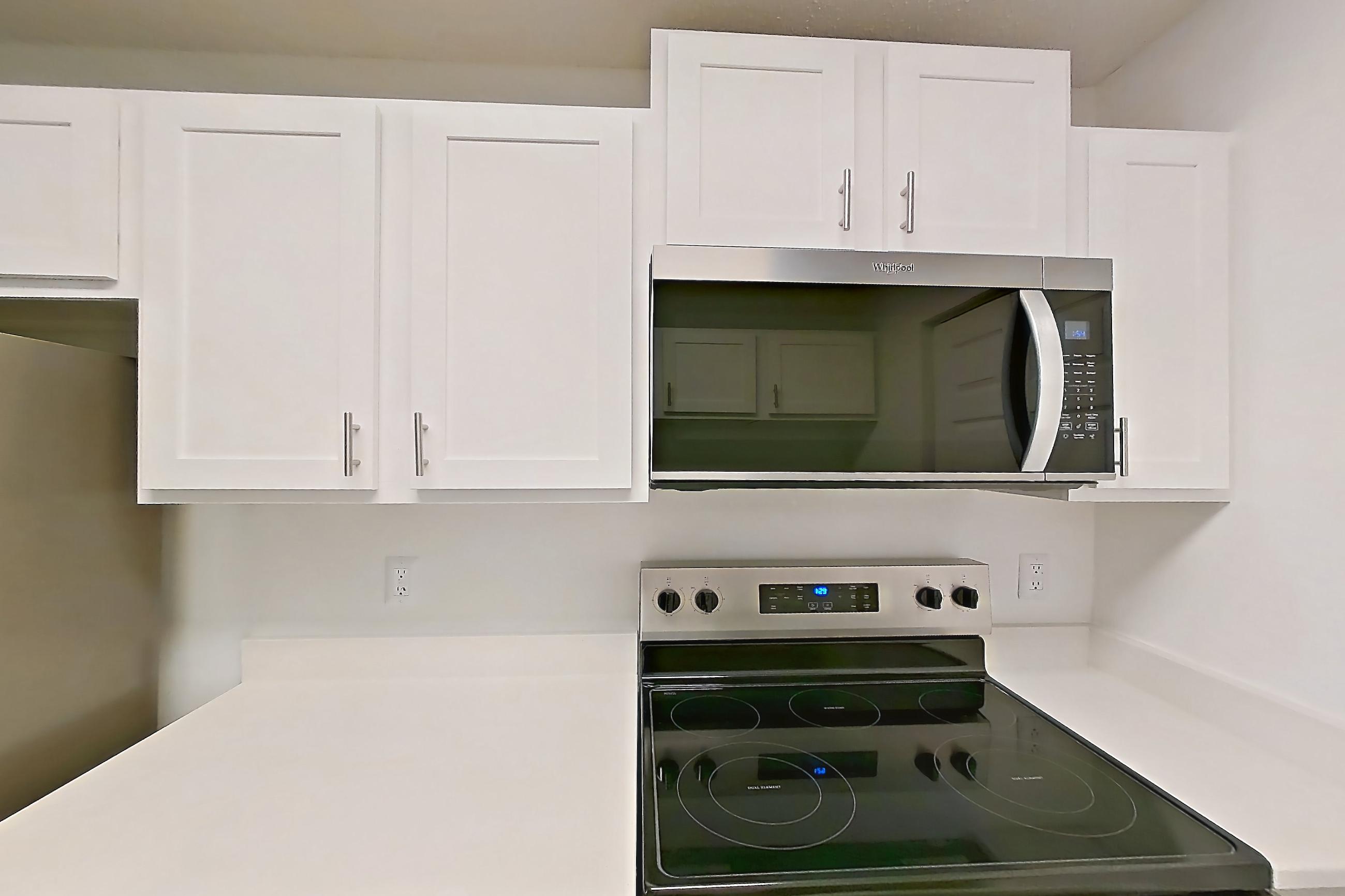 Kitchen with dishwasher, electric range, light countertops, light wood-finish flooring, oven/range, refrigerator, and stainless steel appliances, Apartment 61-B08 at Crosstown at Chapel Hill