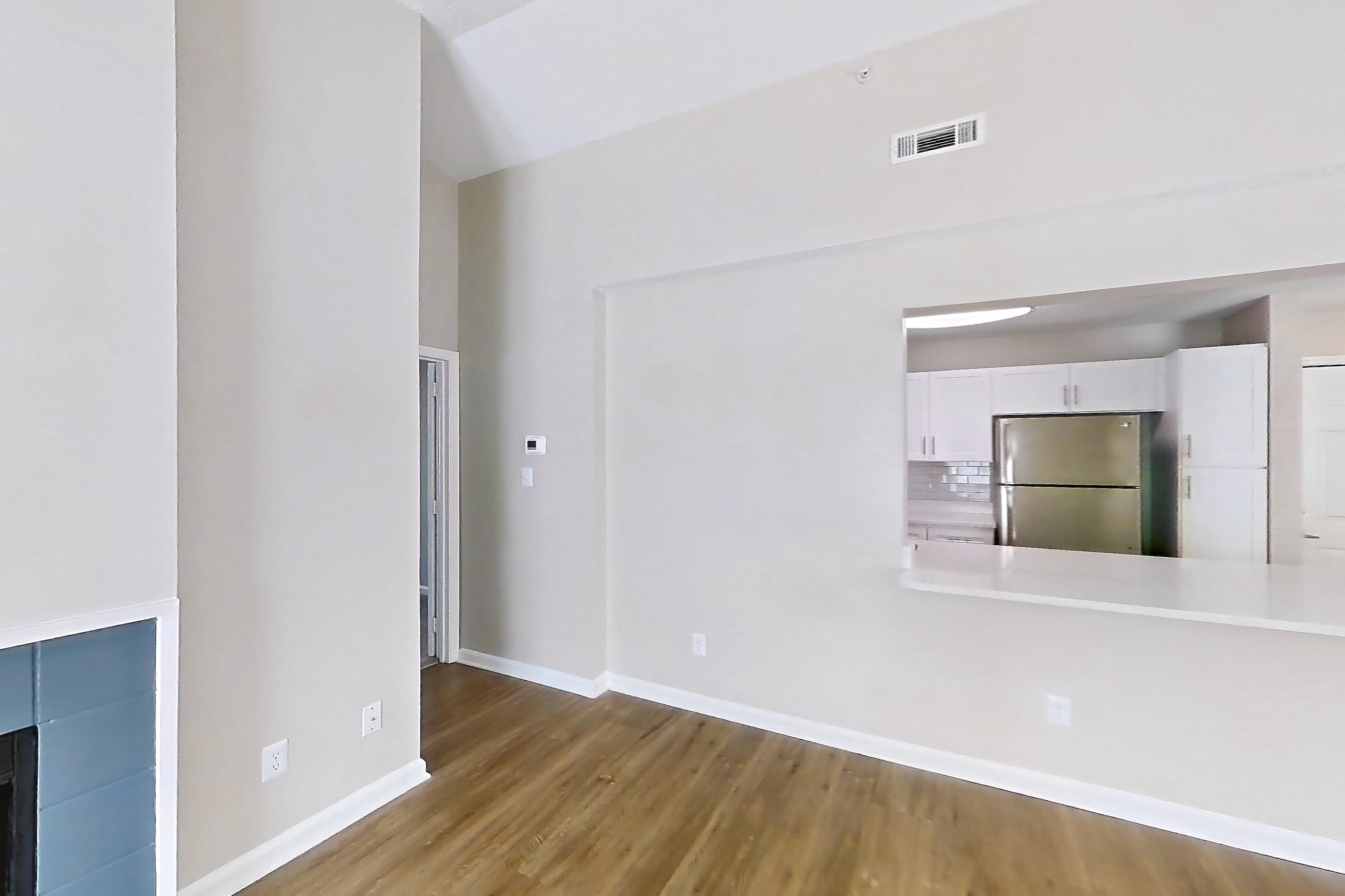Living room with fireplace, light wood-finish flooring, refrigerator, stainless steel appliances, and tile fireplace, Apartment 61-I08 at Crosstown at Chapel Hill
