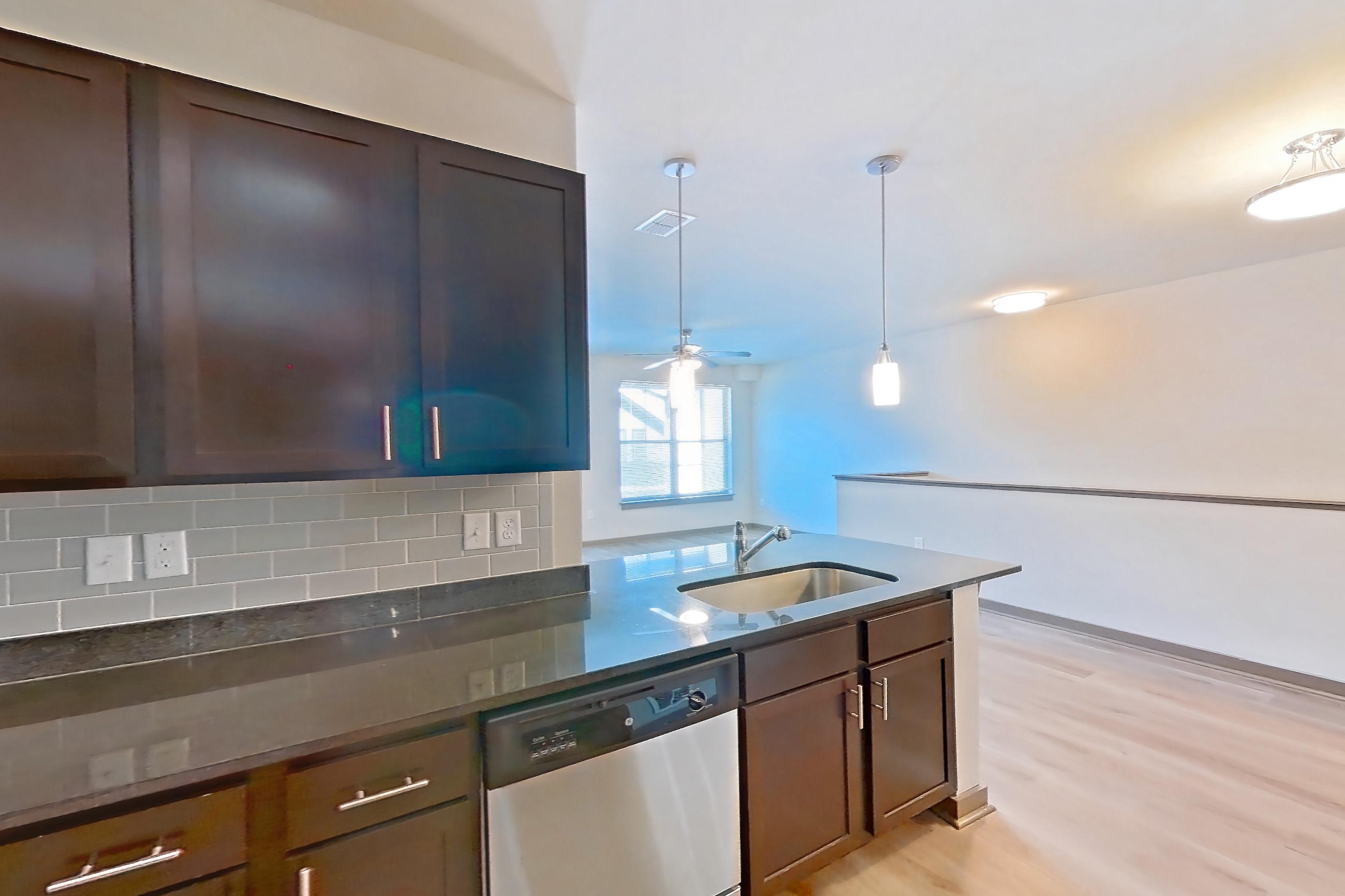 Kitchen with dark stone countertops, dishwasher, electric range, light wood-finish flooring, microwave, oven/range, refrigerator, and stainless steel appliances, Apartment 800-203G at Park 9