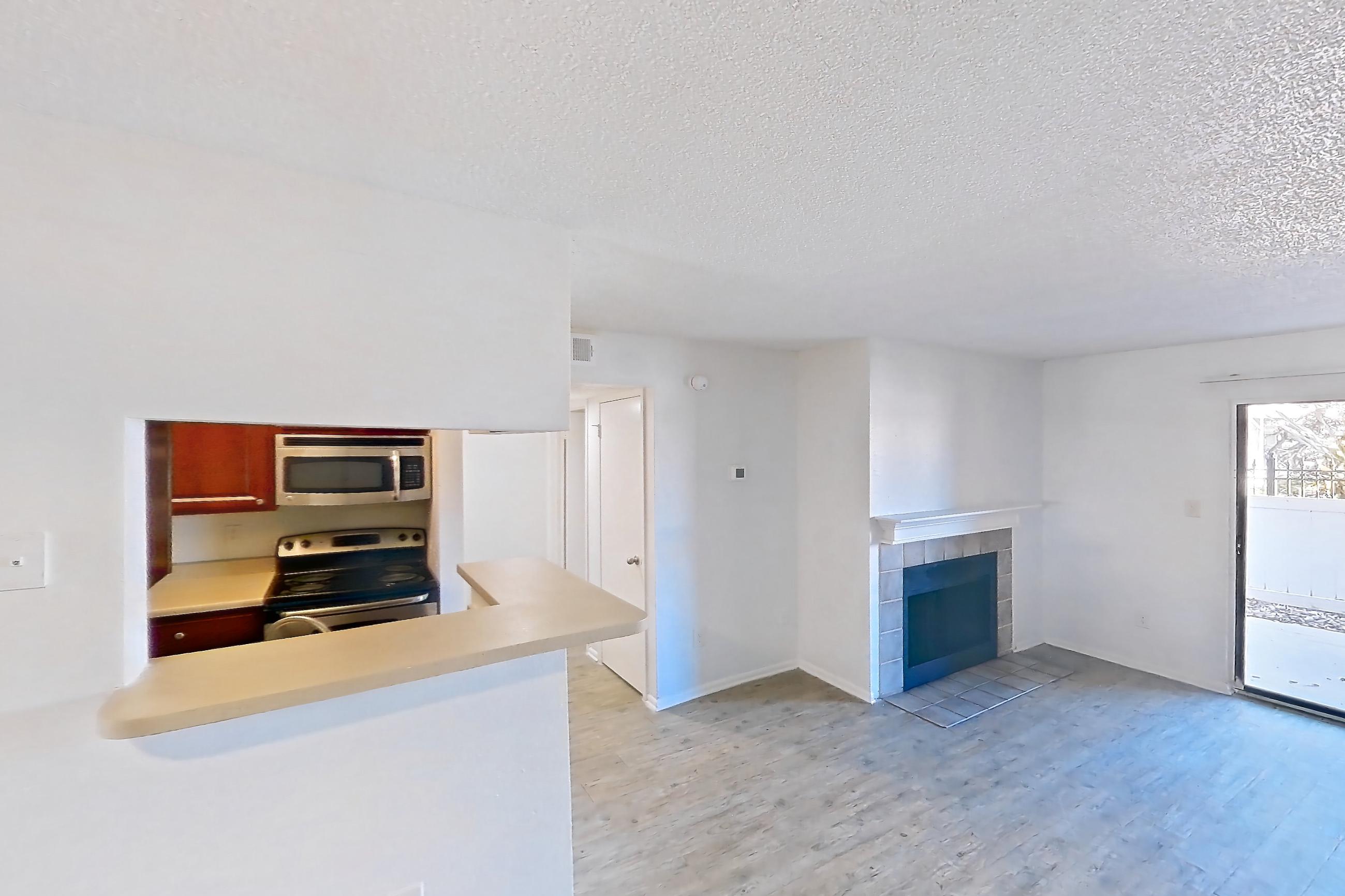 Living space with electric range, fireplace, light countertops, light wood-finish flooring, microwave, oven/range, stainless steel appliances, and tile fireplace, Apartment 09-108 at St. James Crossing