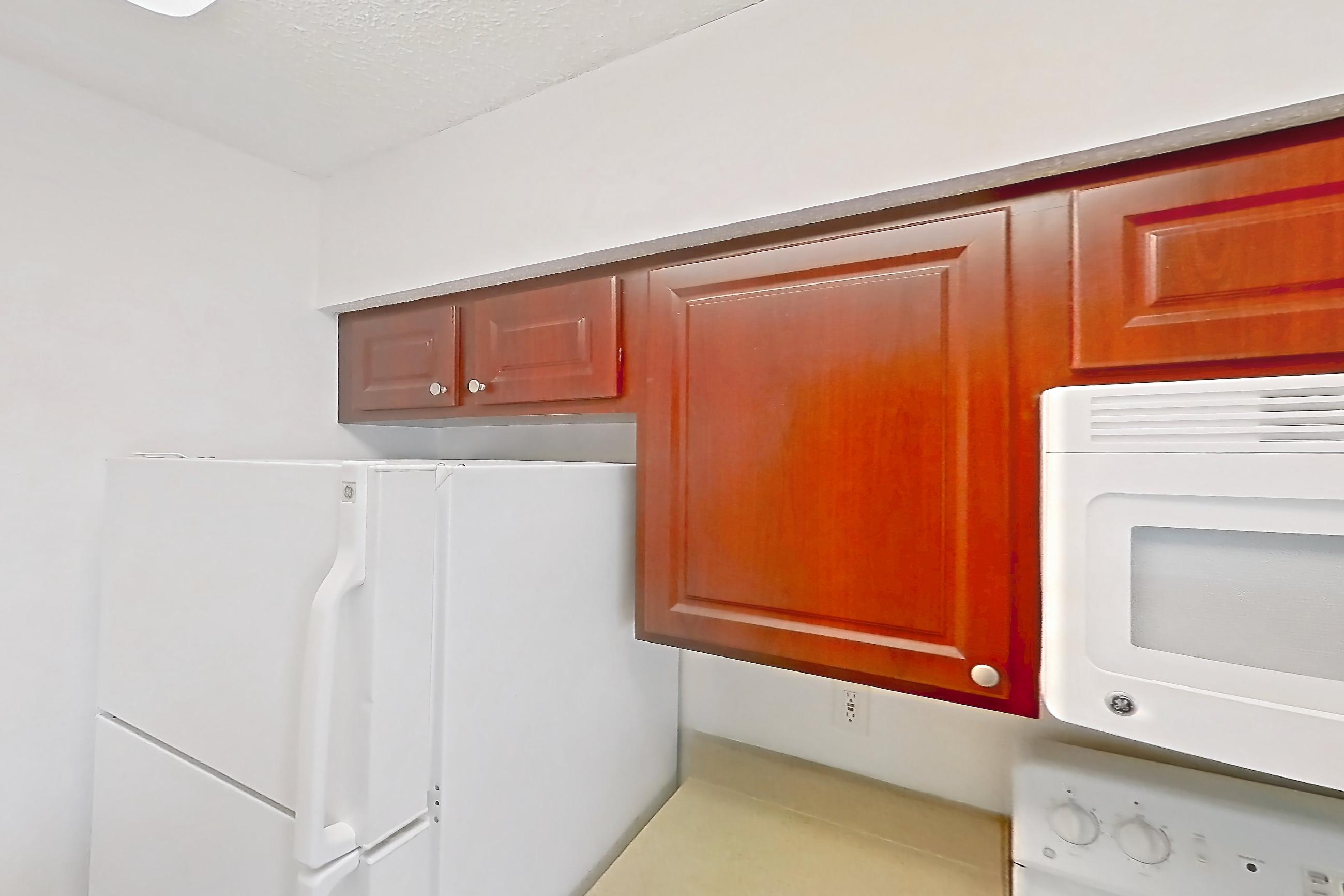 Kitchen with dishwasher, electric range, light countertops, light wood-finish flooring, microwave, oven/range, refrigerator, and white appliances, Apartment 09-204 at St. James Crossing